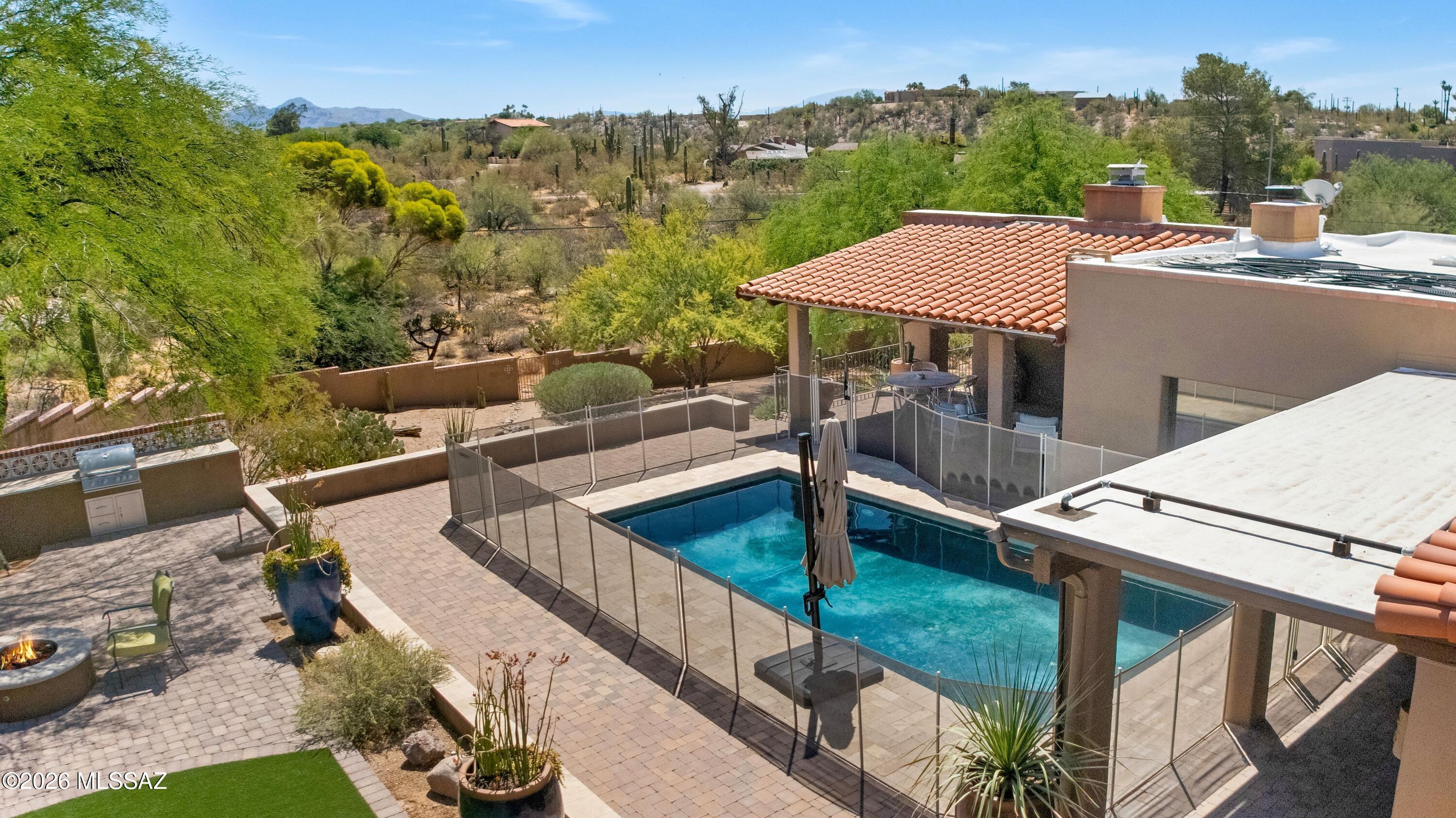 Tucked into the historic neighborhood of Catalina Foothills Estates is this serene Hacienda style home w/high exposed wood beamed ceilings, decorative doorways, modern concrete floors throughout, remodeled chefs kitchen w/butlers pantry, ample outdoor entertaining areas & so much more. This home is a blend of views, nature, comfortable luxury living, natural light & an outdoor paradise.  Enter through a courtyard w/fountain at the entrance, onto a front veranda into the home where you'll find high wood beamed ceilings, fireplace and large living/dining room.  Kitchen is open w/high ceilings, huge island, 2 sinks, gas range, subzero fridge, overlooking the family room/fireplace & adjacent to the butlers pantry w/additional dishwasher, beverage drawer & 100 bottle wine fridge. Primary Suite w/fireplace, huge walk in closet, bathroom has dual sinks, jetted tub & separate shower w/steam shower feature. Outside beautiful pebble tec pool w/natural stone & pavers surround, gas fire-pit, artificial turf, Sport Court for basketball / pickle ball, a Casita w/bathroom for guest use or gym, numerous outdoor entertaining areas w/Mountain Views & 2 car detached garage features an electric car charger & storage.  This property has sought after Catalina Foothills Schools, close to hiking trails, biking, premier shopping, restaurants, & just 15 mins to downtown & UA. This home truly has it all