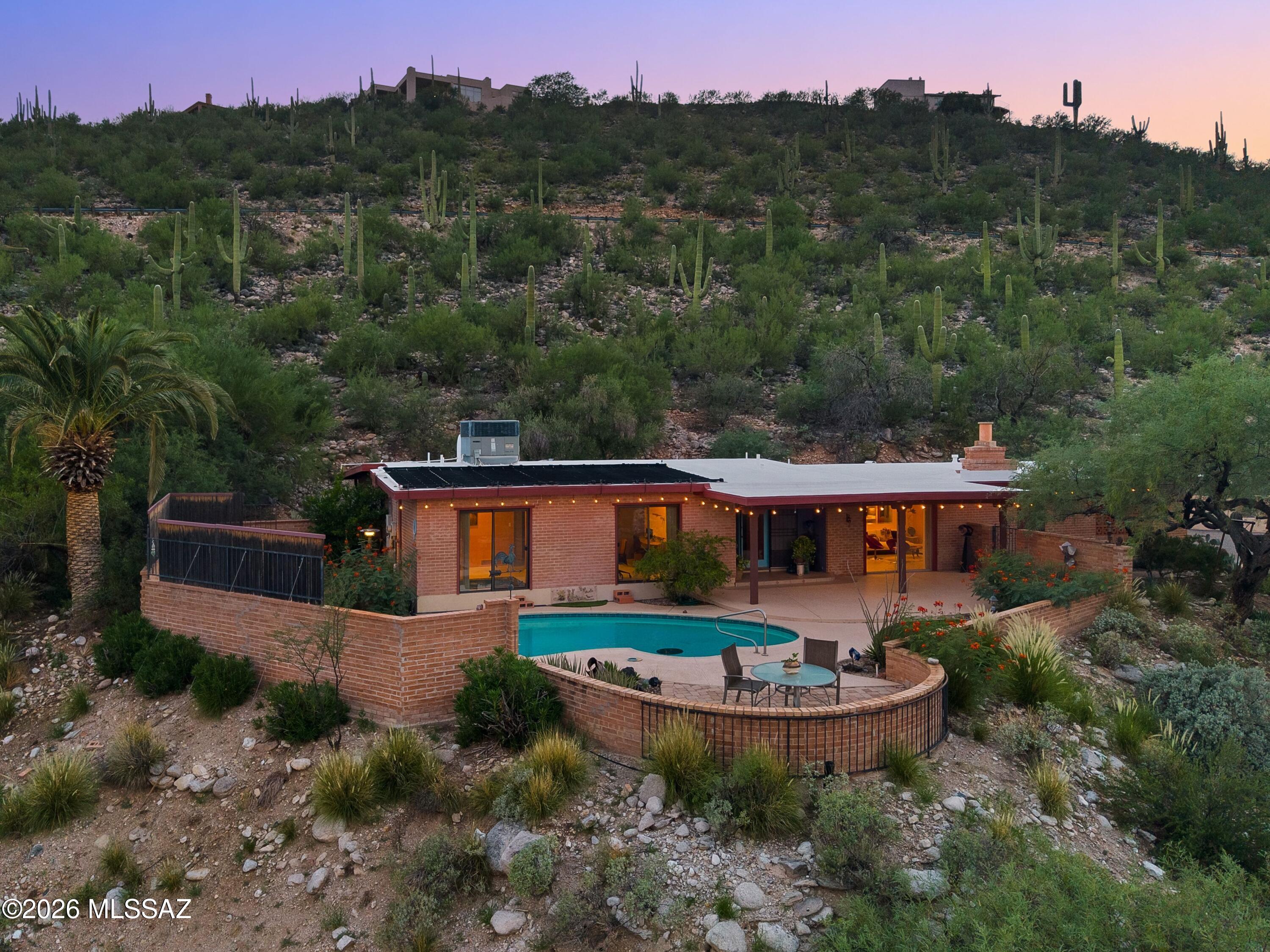 Mid-century modern 3 BR, 2.5 BA home with a large den, built into a private hillside on 1.3 acres in the coveted subdivision of Hidden Valley. Fully updated with today's finishes, the home captures panoramic Santa Catalina Mountain and valley views from nearly every room. The open kitchen features a mosaic glass tile backsplash, stainless steel appliances including a French-door refrigerator and gas range, and light wood cabinetry, opening directly to the living and dining areas around a brick, wood mantled fireplace. The primary suite includes an infrared sauna and en-suite bath. Outside, a solar heated pool and covered, string-lit patio create an entertaining space framed by mature saguaro, prickly pear, and mesquite trees.  The 1.3-acre desert lot offers exceptional privacy and mature, low-maintenance desert landscaping throughout.

Walking distance to Wes Miller Park, a natural-habitat preserve donated to the Hidden Valley Homeowners Association by the subdivision's developer and protected under a conservation easement with The Nature Conservancy as part of the Sabino Creek ecosystem. Set in the Hidden Valley area of Tucson, the home is also minutes from Sabino Canyon, Ventana Canyon, and the shops and restaurants along Sunrise Drive and Skyline Drive.

Come experience mountain-view living in Hidden Valley -- schedule your private tour of this Tucson, Arizona hillside retreat today.