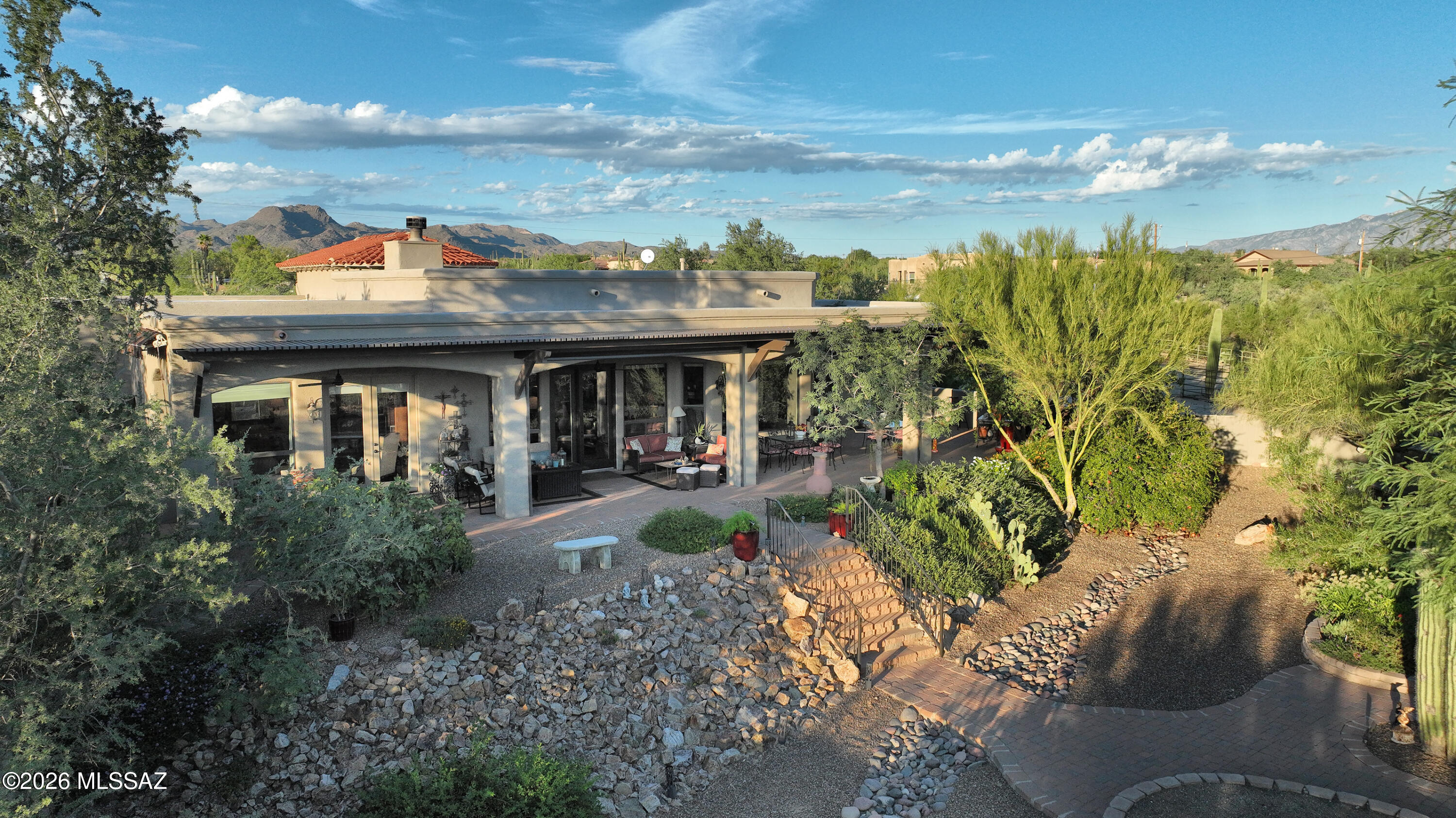 Very private & resort-like, this custom-built Northwest Tucson residence captures the essence of elegant desert living. Nestled on 2 acres surrounded by lush native flora & fruit trees, this exceptional horse property showcases breathtaking 360 views of the Catalina Pusch Ridge, Tortolita, & Tucson Mountains with sparkling city lights to the South & magnificent sunrises & sunsets painting the desert sky in every direction. The terraced wraparound patio, complete with remote-controlled electric shades & eyebrow extensions, provides an idyllic setting for a morning coffee or evening gatherings. Inside, the spacious 4-bedroom, 3-bath split-bedroom design features soaring 12-foot ceilings, walls of windows framing stunning mountain views, & a grand sense of space and light throughout. The gourmet kitchen is a showpiece perfect for entertaining with an induction cooktop, Bertazzoni telescopic hood, granite countertops, and a generous breakfast bar. Elegant granite executive-height vanities and custom Knotty Alder cabinetry flow throughout, highlighted by a striking 8-foot solid entry door. The open great room centers around a warm wood-burning fireplace and newer French doors provide access to outdoor living spaces. A private guest suite with its own wing and entrance offers exceptional flexibility for multi-generational living or extended guests. Zoned for horses and complete with horse facilities. This Electric Energy Efficient home has an owned Solar System with net metering. Ideally located near The Loop multi-use path, Catalina State Park, The Gallery Golf Club, The Highlands Golf Club, and Tortolita Mountain Park, & Preserve, this property offers an unparalleled blend of serenity, privacy, and proximity to some of Tucson's most stunning recreational destinations. Only minutes from I-10, Shopping and Restaurants. (Be sure to view the video at the tab)