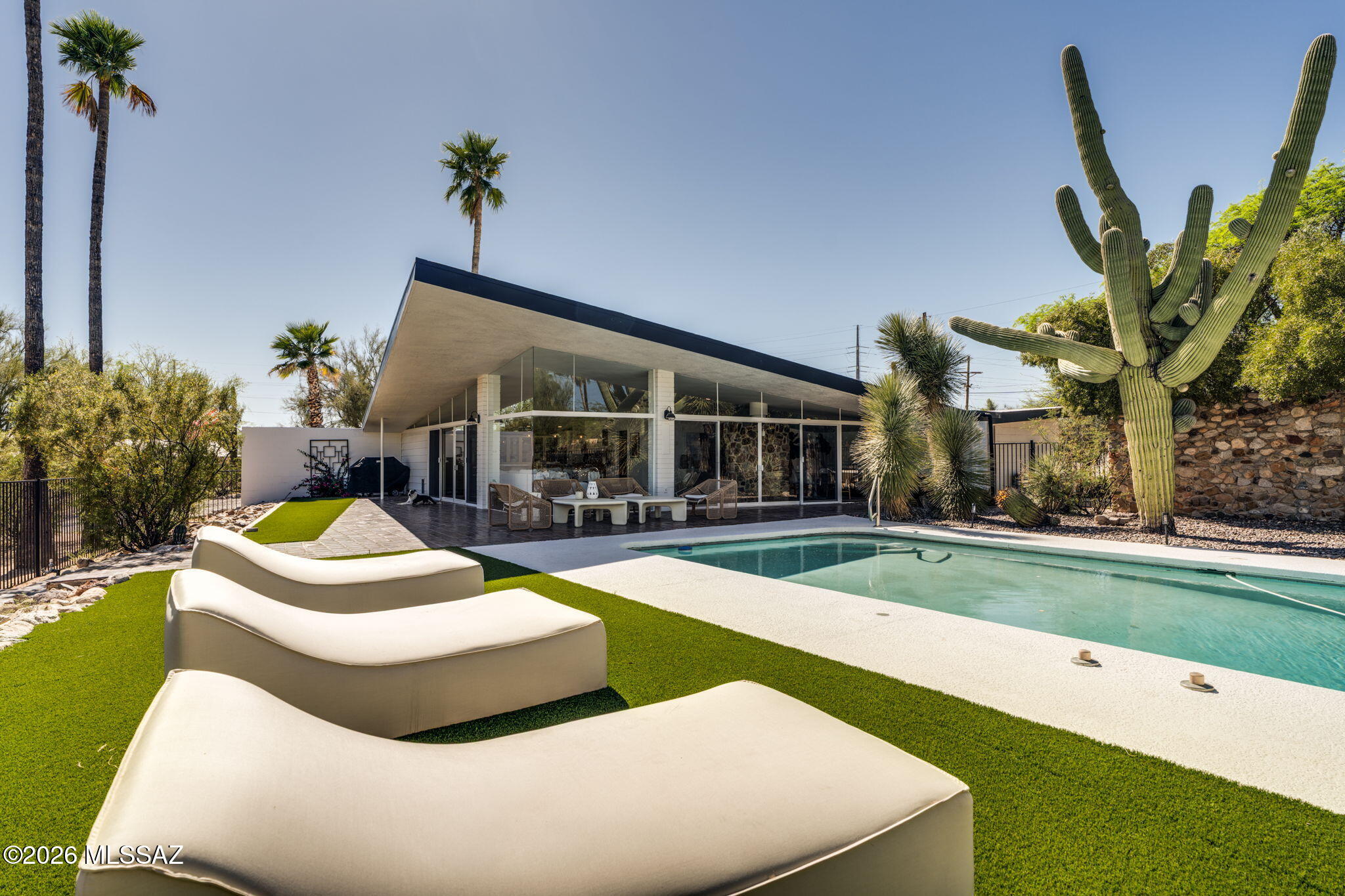 Welcome to a one-of-a-kind Tucson treasure that will stop you in your tracks. Thoughtfully designed to frame sweeping views of the Catalinas, towering Saguaros, and pool, this architecturally distinctive home delivers the effortless glamour of Palm Springs right here in the heart of the desert. Inside, warm Saltillo tile flows seamlessly from room to room and right out the door, creating a natural indoor-outdoor connection that feels both timeless and intentional. The fully reimagined kitchen is a showstopper, featuring leathered marble countertops, glass-front cabinetry, and stainless steel appliances. A generous bar or pantry just off the kitchen offers custom built-in shelving, perfect for the entertainer at heart. The primary suite is a true retreat, spacious and serene, with views overlooking the outdoor fireplace, a large walk-in closet, and a beautifully appointed bathroom. Two additional bedrooms and three total bathrooms provide flexible space for family, guests, or a home office. An oversized laundry room with custom built-ins and a full bathroom adds everyday convenience you'll appreciate.
Step outside and discover multiple entertaining spaces designed for Tucson living at its finest: a custom pool with a daybed lounge area made for long desert afternoons, a custom fireplace for cool evening gatherings under the stars, and mature desert landscaping that creates lush, dramatic beauty around every corner. No HOA. Situated in a wonderful family neighborhood within walking distance of Harelson and Cross schools and a community pool, with easy access to shopping, dining, and everyday essentials.

This home has been deeply loved -- and it's ready to give that same feeling to its next owner.

Owner/Agent