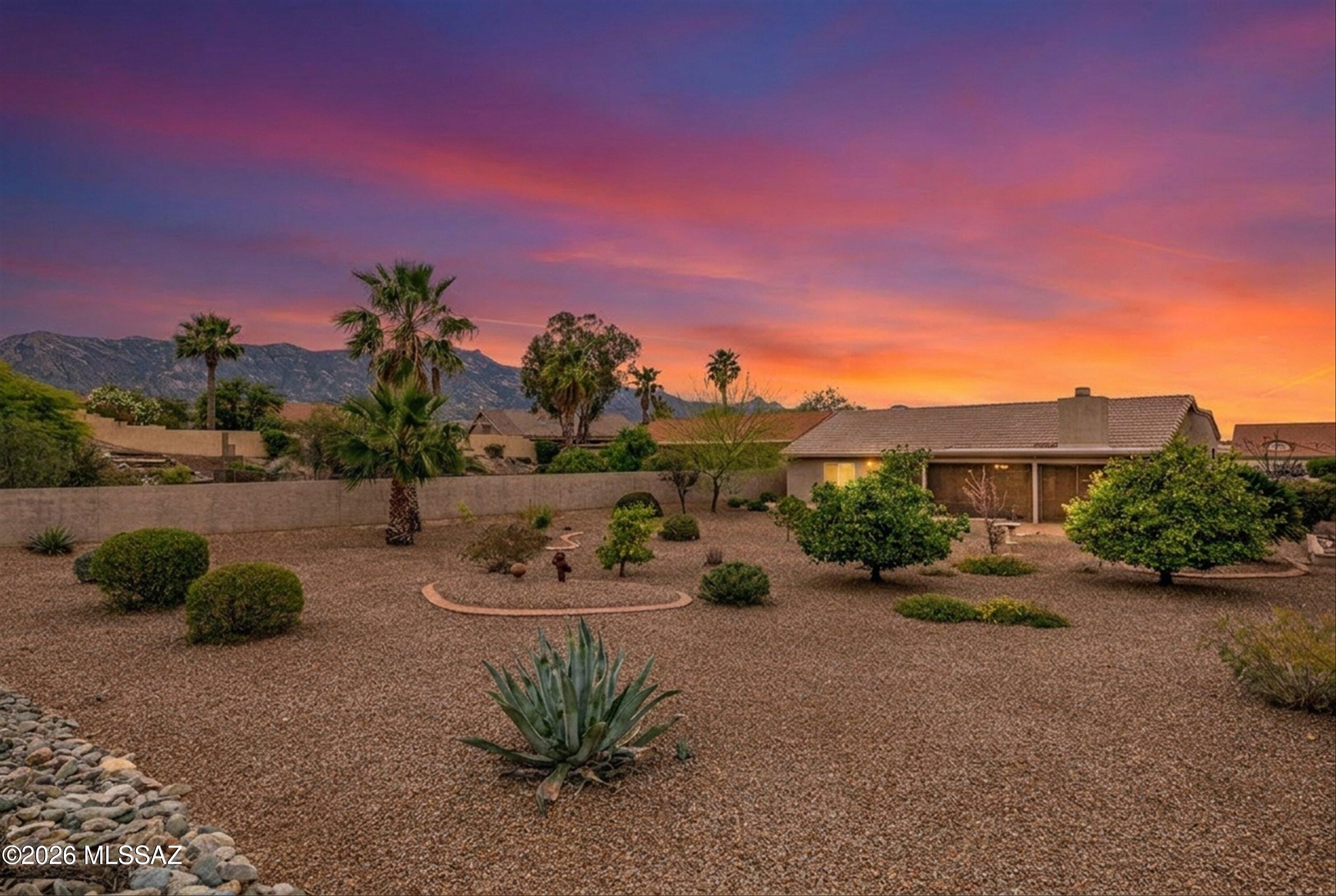 Located in SaddleBrooke's premier active adult community, this expanded Topaz model offers 3 bedrooms and 2 bathrooms with flexible living space. The family room features a cozy fireplace, plus a second outdoor fireplace for Arizona evenings. The 2nd bedroom serves as an office with a built-in Murphy bed, while the primary and 3rd bedroom include oversized walk-in closets. The spacious kitchen showcases granite countertops, a beautiful backsplash, breakfast bar, and eat-in area open to the family room. A welcoming foyer leads to a bright living room and formal dining space. Enjoy a screened-in patio on a third of an acre lot with room for a pool or casita. Updates include freshly painted interior & extended garage, new roof underlayment/recoated patio roof('25), owned solar, & no carpet.
