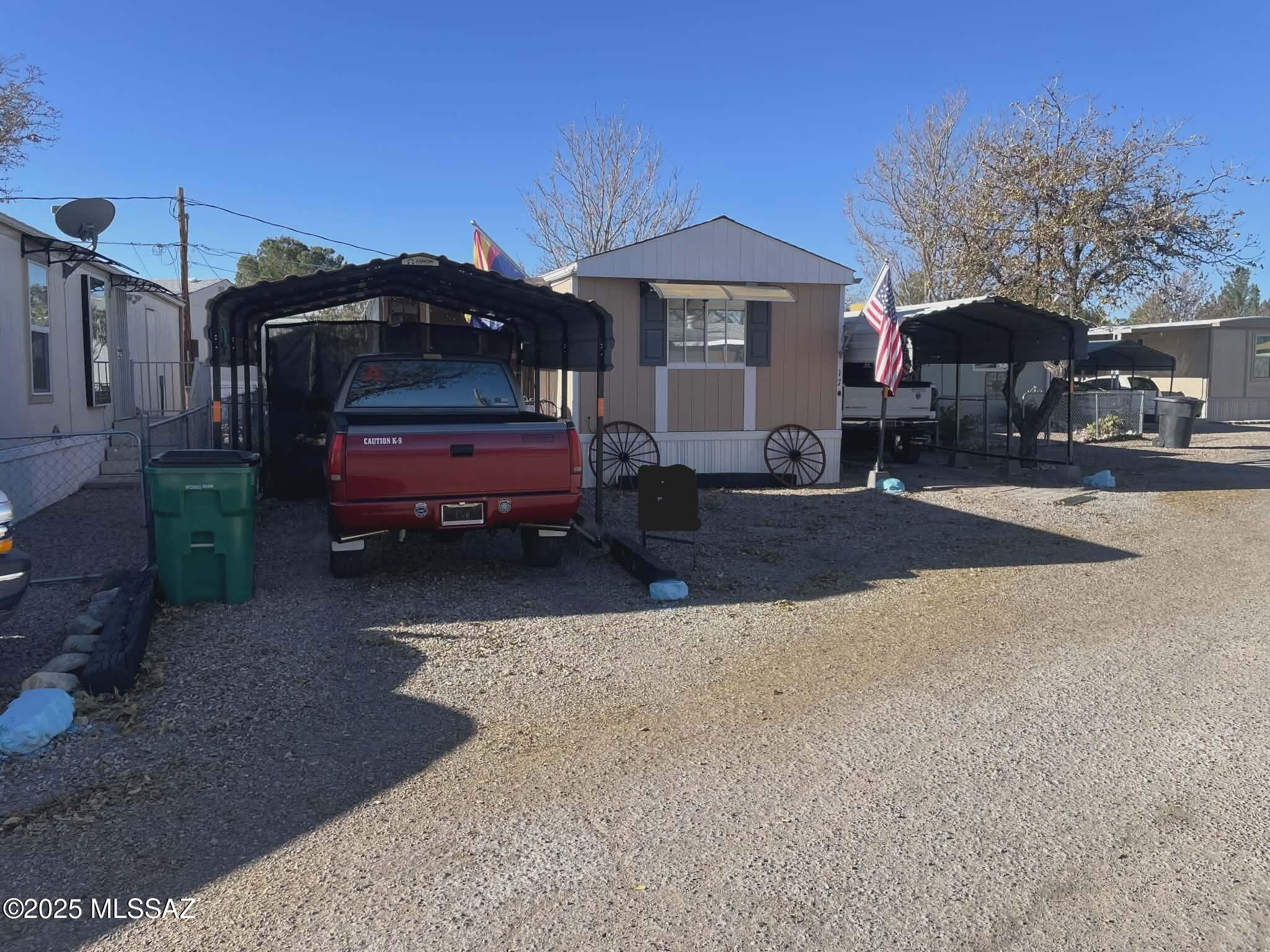 This well-maintained 2-bedroom, 1.5-bath manufactured home is located in a quiet 55+ park on leased land, with lot rent at just $400/month The home features a spacious screened-in Arizona room, perfect for relaxing or entertaining year-round. Enjoy outdoor living with a full outdoor kitchen, new gutters, and security lighting for added peace of mind. With three carports and space to park up to four vehicles, there's room for all your guests. The beautifully landscaped yard showcases native cacti and large shade trees, creating a low-maintenance desert oasis. A convenient shed provides extra storage. Ideally situated close to shopping and other local amenities.
