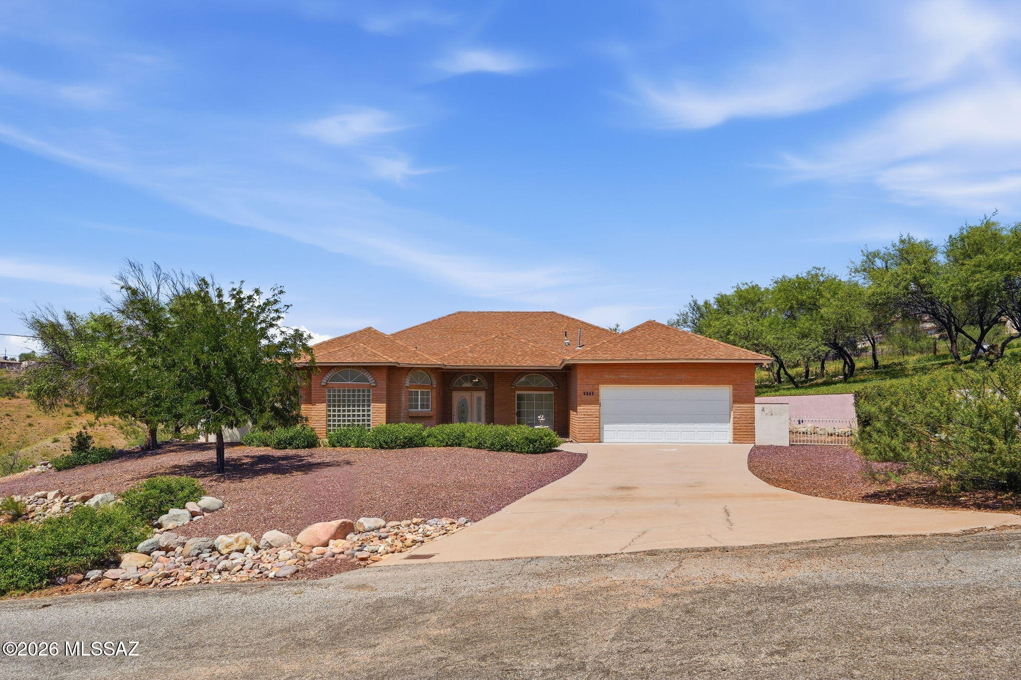 Welcome home to this private brick home situated on 1.78 acres with beautiful views and plenty of room for family, friends, and entertaining. From the moment visitors arrive, they will appreciate the inviting curb appeal, mature landscaping, and peaceful setting that make this property feel like home. Inside, a three-year-old HVAC system keeps you comfortable year-round while the open floor plan provides an easy flow throughout the home. With an entertaining room, spacious living room, office/den, hobby room, 4 bedrooms, & 3 bathrooms, there is plenty of space for everyone to spread out while still enjoying time together. The spacious kitchen offers ample room for preparing meals along with a granite breakfast bar that is perfect for enjoying your morning coffee while catching up on the day's news. Three separate doors provide convenient access to the expansive backyard, which is completely enclosed with block and iron fencing, creating a wonderful space for children and pets to play. Mature trees in both the front and backyard provide welcome shade and the relaxing sound of the breeze, while the home's elevated setting showcases majestic views of the canyon and wash below. Wildlife is abundant throughout the area, with deer, javelina, and a variety of birds frequently making an appearance. Follow the decorative rock pathway a short distance from the home to your own covered observation area with a bench overlooking the canyon and valley--the perfect place to enjoy your morning coffee, watch the wildlife, unwind at the end of the day, or simply take in the peaceful surroundings. With 1.78 acres, generous indoor and outdoor living spaces, beautiful views, privacy, and room for the entire family, this home offers a unique opportunity at a price designed to sell.