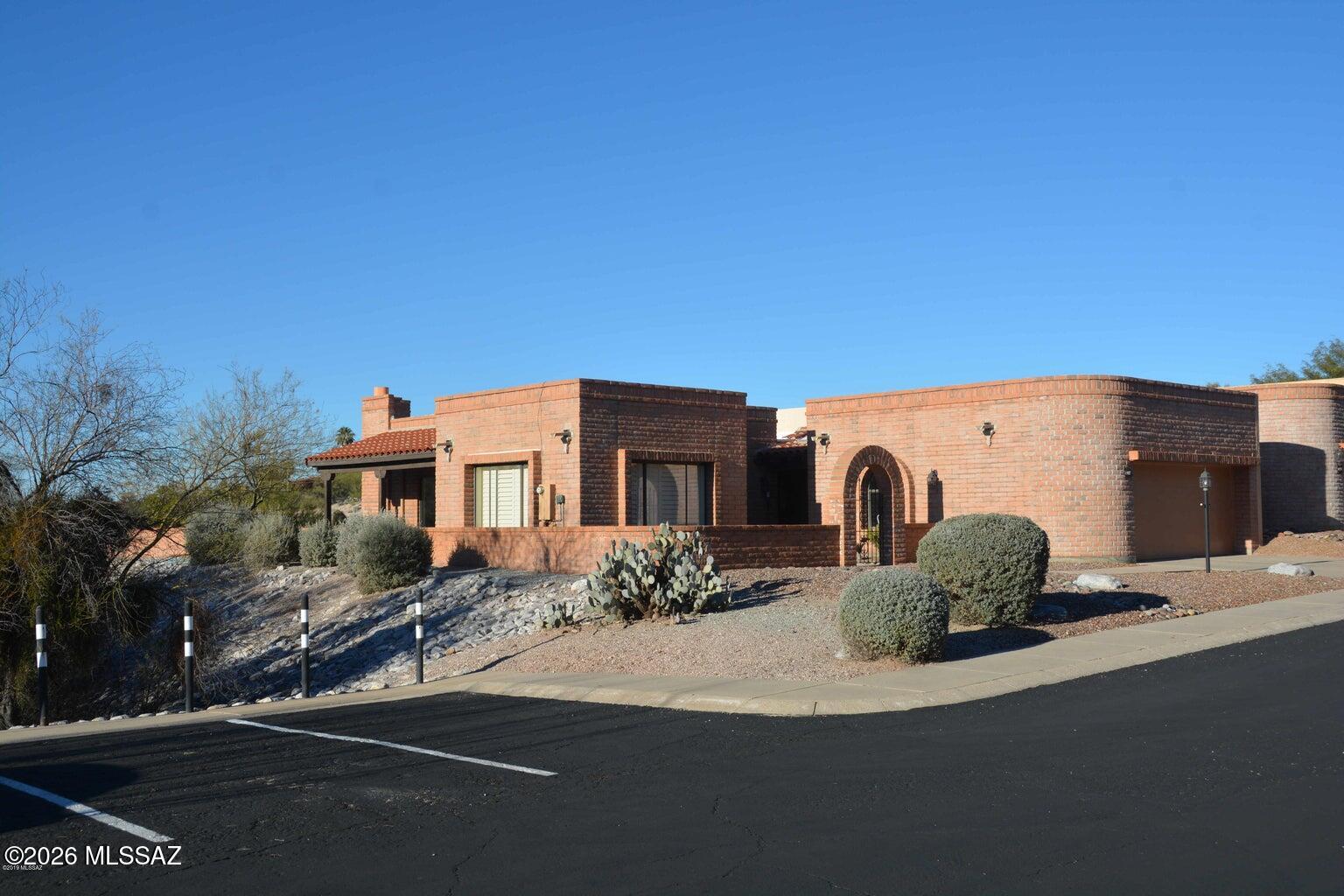 North Tucson living at its finest! End unit San Jose floor plan sitting on beautiful lot above natural green space. This 2 BR, 2 BA beauty has comfortable, well-planned living space on a generous, private lot. Bright, open and airy floor plan includes formal living/dining area and separate flexible and functional den or office off the kitchen. Kitchen features granite counter-tops, beautiful cabinets, and LG Stainless Appliances. Primary suite provides a sense of retreat, complete with a modernized ensuite bath and spacious walk-in closet. Guest and primary baths feature executive height counters. Many upgrades including extended electric awnings and drop down screens on back patio; plantation shutters and verticals throughout; recirculating pump on the water heater; artificial turf on south lawn; gas heat and gas water heater; security door at front entry; sun tint on some windows; recent roof maintenance with 2 year warranty. AC was replaced in 2013 and has a current maintenance agreement. Washer, dryer, and refrigerator convey. Expansive backyard is great for entertaining guests or a quiet evening enjoying the magnificent Tucson sunsets and sparkling city lights. Additional guest parking spots are available just steps away. Convenient to Foothills restaurants, shopping, and top-rated trails, all within easy access.