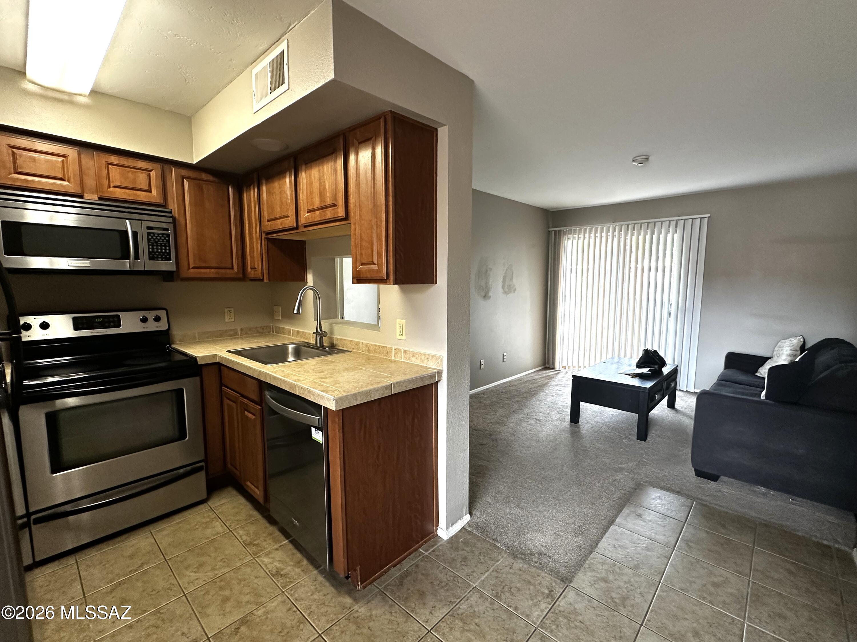 Convenient location near The University of Arizona, 1-bedroom, 1-bath corner, 1st floor unit for easy access. This unit is within very close proximity to one of the community pools in the complex. The unit features tile/carpet flooring throughout. Brand new AC unit installed in 11/2024, open dining area to living room, updated kitchen with raised panel kitchen cabinets, tiled countertops, and  stainless steel appliances. Updated bathroom with new vanity and tile surround in the shower. Accessible patio from both living room and bedroom with storage closet outside. Community amenities include multiple pools and spas, tennis courts, a fitness center, and community laundry facilities. The property offers convenient access to U of A, shopping, dining and other amenities.