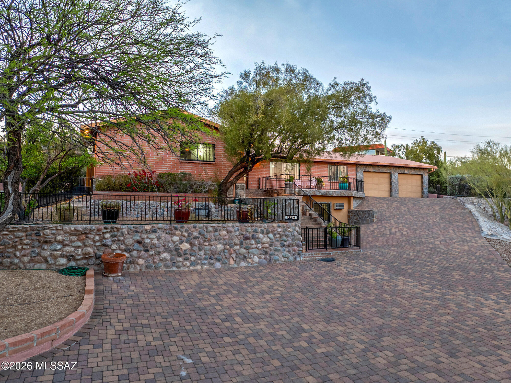 Classic Southwest charm meets space, function, and thoughtful upgrades! This solid brick ranch home welcomes you through a private gate to an expansive paver driveway, abundant parking, and both an attached 2-car garage plus a separate 2-car garage--ideal for vehicles, hobbies, or storage.  Inside, the versatile layout offers flexibility for the way you live. The main level is complemented by a lower-level office suite featuring a front reception area and a private back room--perfect for a home office, studio, or guest space. Enjoy both formal and casual living and dining areas, anchored by an updated kitchen with stainless steel appliances, hickory cabinetry & granite countertops. The spacious primary suite features an updated bath with a jetted tub and separate walk in shower and dual vanity.  Step outside to multiple patios designed for taking in breathtaking sunsets and mountain views. The mature, desert-inspired landscaping creates a private, serene setting, with a set of stairs leading to the top of the backyard--where you'll fully appreciate the natural beauty and surrounding desert life.  Major mechanical upgrades add peace of mind, including a durable metal roof, newer HVAC system, and tankless water heater.  Private gated entrance.
