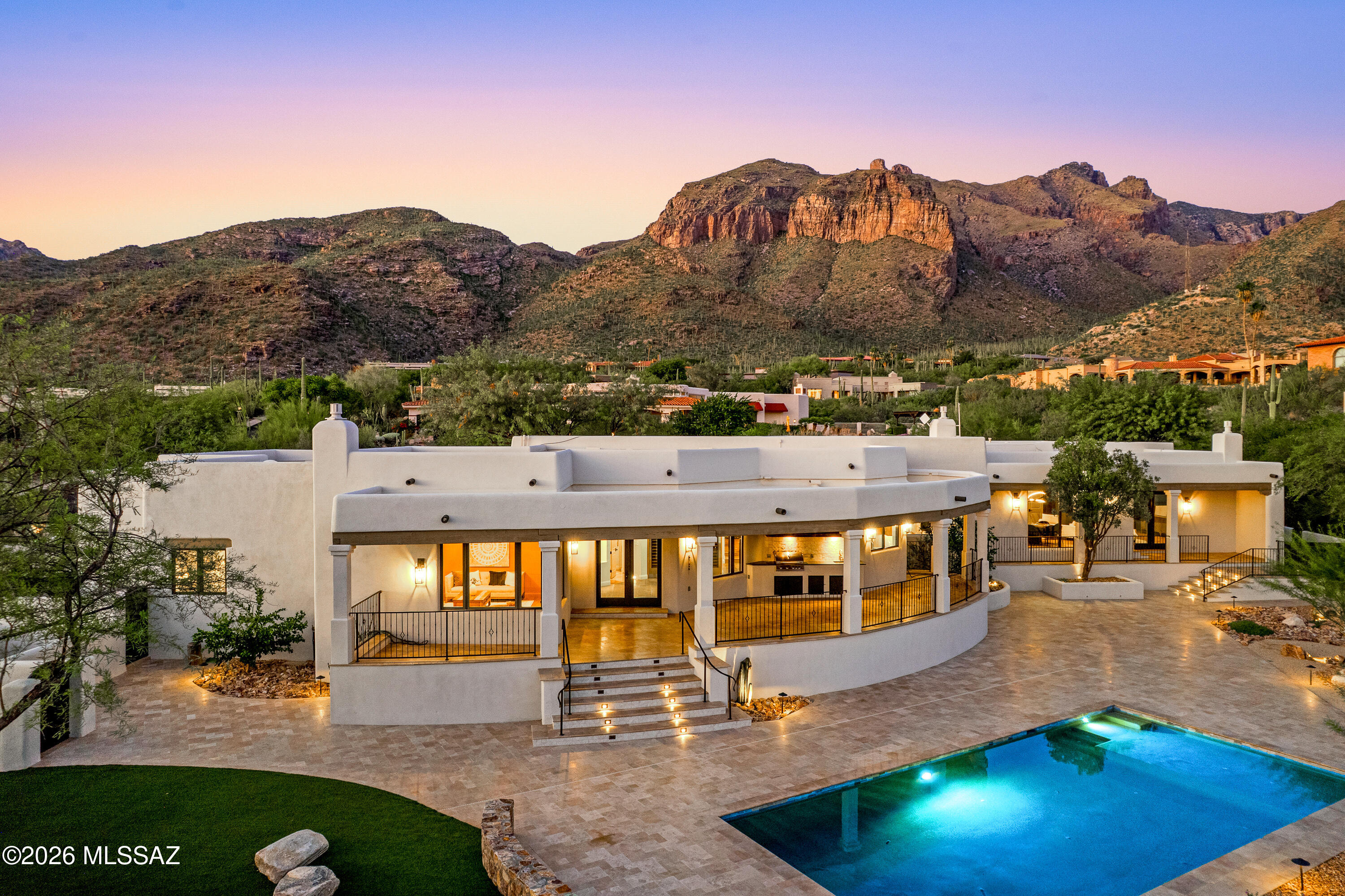 Welcome to Casa Bella Vista in the Catalina Foothills. This modern Santa Barbara style estate is a masterwork of design and detail, showcasing over $2 million in bespoke upgrades. From the moment you arrive, the private courtyard opens to sweeping mountain vistas, blending timeless architecture with refined elegance. Inside, soaring ceilings and walls of glass capture both mountain and city views, while custom Italian finishes, curated materials, and artful craftsmanship create a residence of unparalleled sophistication. The heart of the home centers on a chef's kitchen with professional appliances and seamless flow into expansive living and dining areas. Five bedrooms and four and a half spa-inspired baths provide privacy and comfort, while the primary suite offers a true retreat with breathtaking views and a sanctuary-like bath. Outdoors, resort-style living unfolds. A shimmering pool is set against the backdrop of glittering city lights, framed by lush turf, mature trees, and multiple entertaining terraces. Two covered patios, including a fully appointed outdoor kitchen invite year-round gatherings, while the elevated setting delivers vistas few can rival. Every element of this estate was designed to inspire, indulge, and impress.