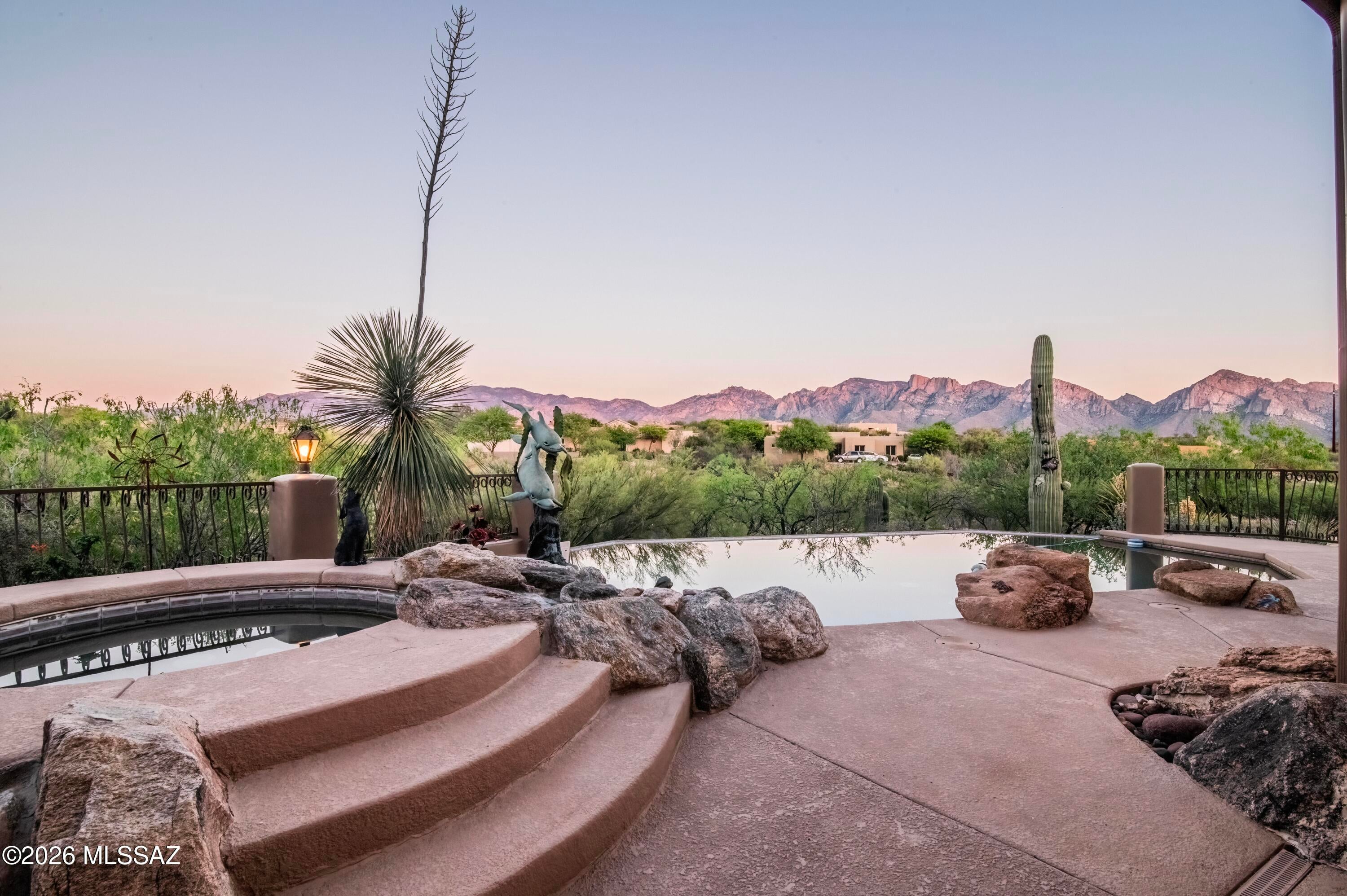 Perched high in the coveted Coyote Ridge enclave of Oro Valley, this extraordinary, gated estate captures the essence of elevated desert luxury. Privately tucked at the end of a cul-de-sac on a premier 1.2-acre ridge-top lot, the home is surrounded by sweeping, unobstructed views of the Catalina Mountains and Pusch Ridge offering a
level of serenity and privacy that is truly rare. Designed for both grand entertainment and refined everyday living, the outdoor experience is nothing short of spectacular. Multiple covered patios with rich wood beams and corbels frame expansive living spaces, while a custom-tiled built-in BBQ, outdoor shower, and a stunning negative-edge Pebble Tec pool with cascading rock waterfall and spa create a true resort-style retreat.