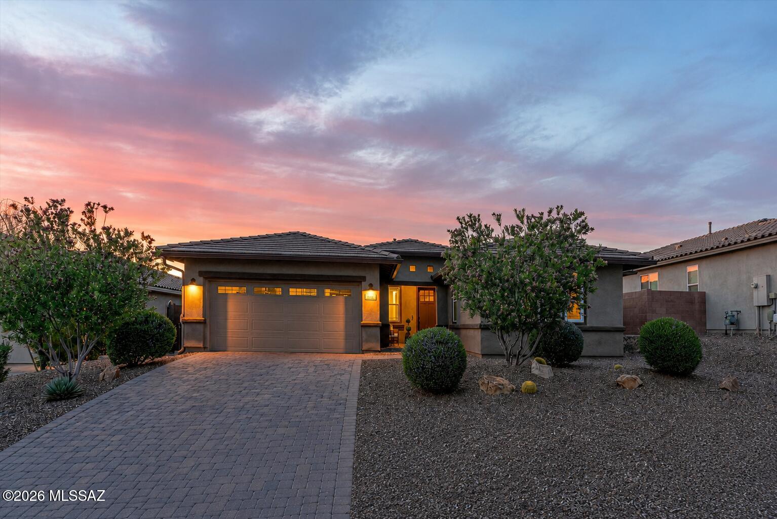 Sophisticated style and understated refinement welcome you to this exceptional residence in the highly sought-after Blue Agave community of world-renowned Dove Mountain's master-planned community. Better than new and meticulously maintained, this stunning 2,519sq ft Ridgeview plan offers 4 bedrooms, 2.5 baths, and a versatile den/office/media room, plus a tandem 3-car garage- all thoughtfully designed to blend comfort, functionality, and elevated finishes.
From the moment you arrive, you'll appreciate your new home's inviting presence and beautifully upgraded front elevation. Positioned on premium Lot 133, which carried a builder lot premium,  your home is complemented by an upgraded paver driveway and entry walkway that add charm and character from the street. Come inside to discover a pristine, bright and welcoming interior finished in a carefully selected neutral designer palette that complements virtually any décor style. Upgraded 8-foot interior doors throughout the home create a sense of volume and custom craftsmanship, while abundant natural light enhances the home's open and inviting atmosphere. Updated lighting fixtures and ceiling fans add contemporary character throughout.
The flexible floor plan has been thoughtfully designed to accommodate a variety of lifestyles. Just off the main living area, the spacious den offers endless possibilities as a home office, media room, study, playroom, or even a potential fifth bedroom. Elegant double 12-lite French doors with sidelites provide privacy while allowing natural light to flow through the space, creating an ideal balance of openness and separation.
The main living areas showcase upgraded Hill House Natural wood-look porcelain tile in a 6x36 format, installed in a premium stair-step pattern and finished with rich walnut grout. Extending throughout the primary living spaces, hallways, powder room, and bathrooms, the flooring delivers both beauty and durability while contributing to the home's cohesive design aesthetic.
At the heart of your home, the expansive great room and dining area offer a warm and welcoming environment for everyday living and entertaining alike. The generous dining space flows seamlessly into the great room and kitchen, providing flexibility to arrange and utilize the space according to your needs. Custom cabinetry has been thoughtfully added, offering valuable storage while introducing texture, warmth, and architectural interest.
The chef-inspired kitchen is enhanced with an upgraded structural layout designed for both functionality and style. Anchored by a grand center island that naturally becomes the gathering place for family and guests, the kitchen features top-tier appliances, reverse osmosis filtration, abundant cabinetry, a built-in desk area, and a charming breakfast nook for more intimate dining experiences. A sleek backsplash adds a polished finishing touch, while carefully selected designer light fixtures contribute to the kitchen's sophisticated appeal. The premium Kohler Cairn single-bowl undermount sink in Matte Black offers both durability and visual impact, while the Arbor oil-rubbed bronze kitchen faucet complements the home's coordinated design selections.
Throughout the home, upgraded oil-rubbed bronze plumbing fixtures create a consistent and timeless aesthetic. Moen Eva series faucets add a layer of quality and refinement to each space.
Split-bedroom configuration provides excellent privacy for family members and guests alike. Three generously sized secondary bedrooms are situated separately from the primary retreat and feature upgraded Level 3 "Sumptuous Cashmere" carpeting paired with a dense premium 8lb Vessel carpet pad, delivering exceptional comfort.  Hall bath has beautiful floor-to-ceiling tile at the tub and shower, creating a more custom and enduring finish. Dual vanities provide convenience and functionality. 
Your primary suite serves as a peaceful sanctuary, offering abundant natural light, spacious proportions, and even a mountain view that adds to the room's relaxing ambiance. The ensuite bath has been designed to evoke the feeling of a private spa retreat. The highly desirable oversized walk-in shower showcases beautiful tile work, a matching tile floor, and a dedicated spa niche for convenience and elegance. Dual vanities provide ample personal space, while the expansive walk-in closet completes this luxurious owner's retreat.
An expansive laundry room with sink, a chic half bath and a dashing mud room area are just off the commodious 3-car tandem garage. Does not get any better than this. 
Outdoor living is equally impressive. Enjoy Tucson's breathtaking sunsets from a backyard designed for relaxation and connection with the surrounding desert landscape. A custom travertine patio surrounds the inviting fire pit, creating the perfect setting for evening gatherings. Artificial turf offers a comfortable surface for recreation and everyday enjoyment, while the extensive covered patio features a sleek epoxy floor coating for durability and style. A natural gas connection makes outdoor grilling effortless, and the view fence enhances the sense of openness while framing the beauty of the desert beyond.
The home also includes several valuable structural and technology upgrades that contribute to everyday convenience and peace of mind. Whole-house surge protection provides advanced electrical safeguarding for your home and devices. A structurally installed 110-volt floor outlet in the great room.  It even has a water softener and gutters!
Beyond the home itself, residents enjoy the unparalleled lifestyle that has made Dove Mountain one of Southern Arizona's most desirable master-planned communities. Nestled against the dramatic backdrop of the Tortolita Mountains, Dove Mountain offers miles of scenic hiking, biking, and walking trails that showcase the Sonoran Desert's remarkable beauty. Residents enjoy access to world-class golf, including courses associated with the renowned Ritz-Carlton Dove Mountain, as well as luxury resort amenities, fine dining, wellness experiences, and year-round recreation.
The community is known for its stunning natural surroundings, dark-sky views, abundant wildlife, and spectacular sunsets. Parks, open space, and thoughtfully planned neighborhoods create an atmosphere that feels both private and connected. Convenient access to shopping, dining, healthcare, and major transportation routes further enhances everyday living while preserving the tranquility that makes Dove Mountain so special. Families benefit from access to Dove Mountain CSTEM K-8 School, a highly sought-after Marana Unified School District campus with a 7/10 GreatSchools rating and a unique focus on computer science, technology, engineering, and mathematics in an innovative, hands-on learning environment.
Combining thoughtful upgrades, flexible living spaces, premium finishes, and an exceptional location, this remarkable Blue Agave residence presents a rare opportunity to enjoy refined desert living in one of Marana's most coveted gated communities.