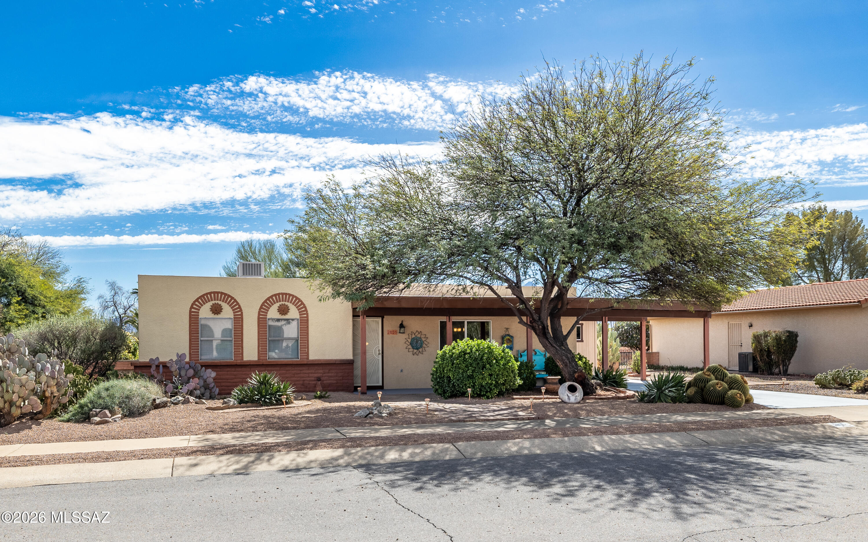You can just tell by looking at the cool  shady tree in front of the house that this charming home is something special. Cozy & comfortable, southwestern style with artistic eclectic touches make this home just right for year round or part-time living. This 1443 sq. ft. has 2 bedrooms, 2 bathrooms, dining area and both a livingroom & a family room. The artistic kitchen features stainless appliances & breakfest bar next to the handy dining area. Step out into the lovely lush enclosed back yard from the family room onto a covered patio surrounded by flowering plants and desert greenery. You can enjoy some back yard mountain views & comfortable patio seating for you & your guests. Then,the laundryroom, just outside the side entry, is large enough for an additional pantry or storage space.