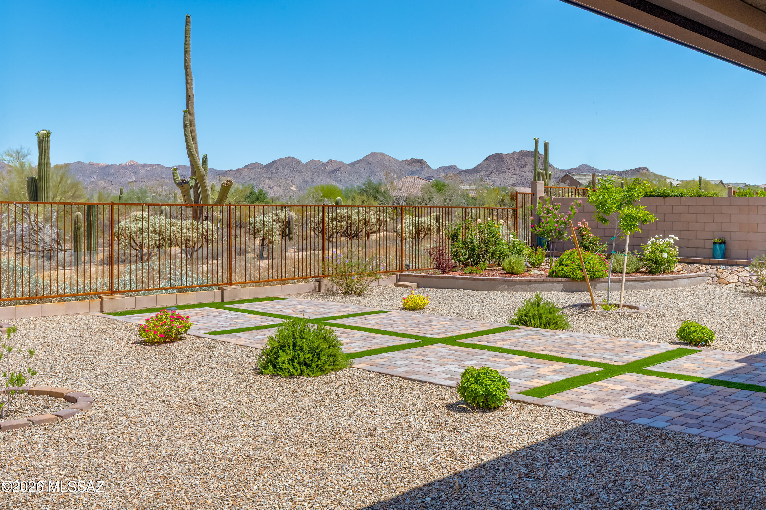 Beautifully positioned in gated Preserve at Twin Peaks, this nearly new Lennar-built home offers the perfect blend of privacy, mountain views, modern comfort & several upgrades. Set on a premium 0.24-acre lot with no rear neighbors, this 4BR, 2½BA, single-story home features 2,598sf of open-concept living & extended 3-car garage. High ceilings & bright, open great room are complemented by dramatic center-opening sliding glass doors, creating seamless indoor-outdoor living. The gourmet kitchen is designed for gathering & entertaining, featuring granite countertops, upgraded cabinetry, stainless appliances, spacious pantry & oversized island. The owner's suite serves as a private retreat with patio access, dual walk-in closets & upgraded bath. Additional bedrooms offer flexibility for guest office space or multi-generational living. The backyard is fully improved with artificial turf, desert landscaping, covered patio space and view fencing, all set against peaceful desert surroundings with mountain and sunset views. The space is primarily finished in decorative gravel, complemented by a geometric layout of large paver pads separated by strips of green turf, creating a visually appealing grid pattern that's ideal for outdoor seating or entertaining areas. With over $90,000 in upgrades including backyard landscaping, patio shades, interior paint, water treatment system, window coverings, and added features throughout this home offers the benefits of new construction without the wait. Conveniently located near Twin Peaks, shopping, dining, parks, and schools, this home delivers the best of Northwest Tucson and Marana living in a secure and desirable gated community.