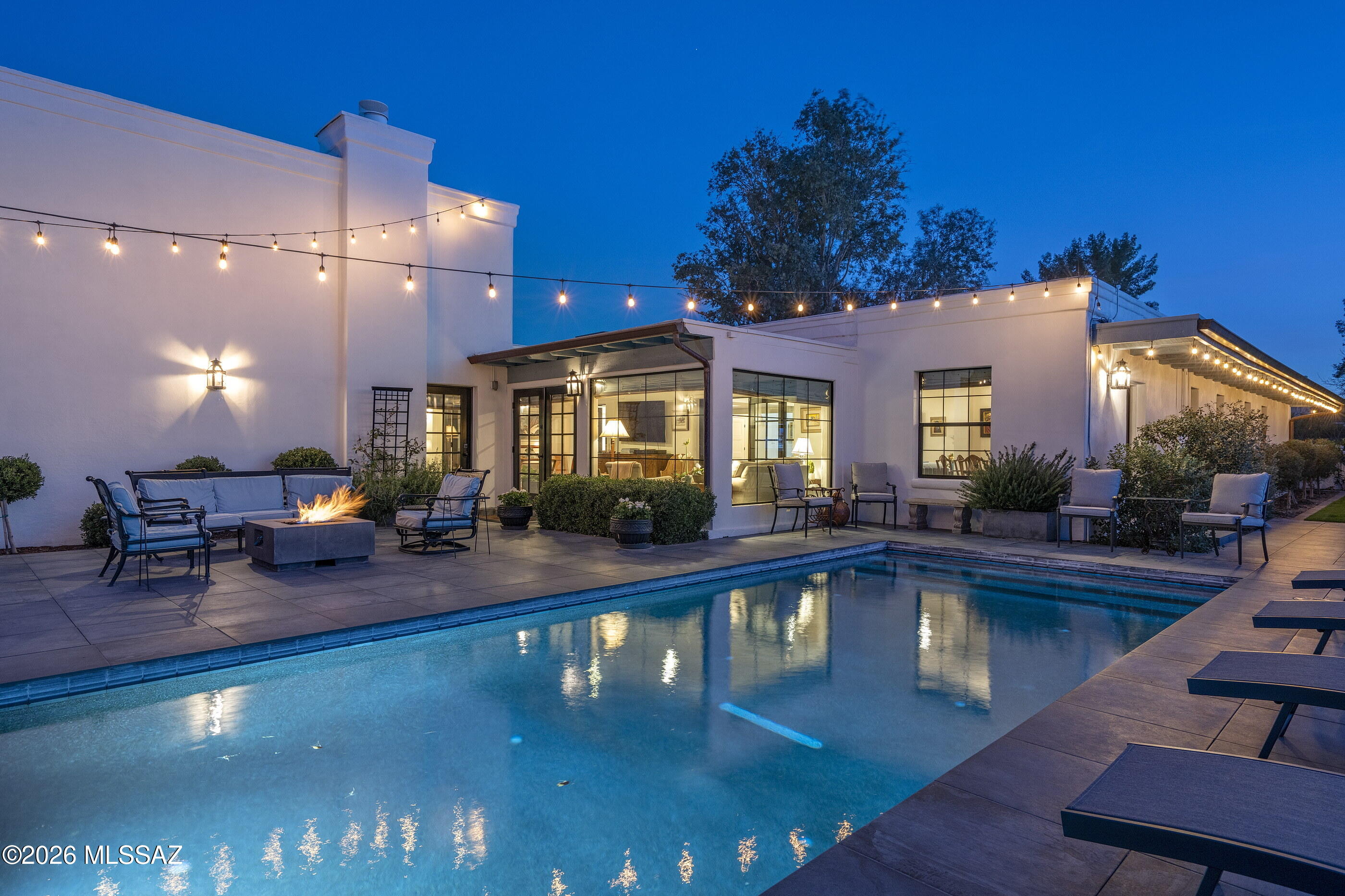 Tucked within the gates of Tucson Country Club, this thoughtfully reimagined 3,993 square foot residence offers a refined yet welcoming presence from the moment of arrival. A lush garden-style courtyard framed by mature plantings, curated flower beds, and a tranquil water feature sets the tone, creating a sense of privacy that feels layered and quietly elegant.

Inside, the home was extensively remodeled in 2021 with a focus on timeless materials and enduring design. Silhouette European Oak flooring carries throughout the main living spaces, grounding the interiors in warmth and cohesion. The kitchen serves as the architectural heart of the home, appointed with white satin marble countertops and premium inset soft-close cabinetry in a sophisticated two-toned white and blue palette. An oversized island anchors the space and invites gathering. Café Series appliances, a farmhouse sink, and custom lighting elevate the room, while a butler's pantry with beverage refrigerator and chevron marble backsplash adds both beauty and function. A built-in desk and wet bar extend seamlessly into the dining area, creating an effortless flow for everyday living and entertaining. The great room is intimate yet open, centered around a gas fireplace and designed to feel comfortable and intentional. Just beyond, a charming sunroom welcomes natural light and offers a graceful transition to the outdoor living spaces.

Two primary suites provide flexibility and privacy. One is designed as a true retreat, complete with an adjoining sitting room highlighted by wood beam ceilings that continue into the over-sized bedroom and marble appointed bath. The second primary suite offers its own sense of retreat, anchored by a gas fireplace and a spacious bath designed for comfort and ease, complete with dual vanities, a soaking tub, separate shower, and dedicated makeup station. Double doors open to a private patio, creating a seamless connection to the outdoors. Two additional bedrooms, one en-suite, provide welcoming accommodations for family or guests.

Outdoors, the property transforms into a secluded desert sanctuary framed by Catalina Mountain views. A newly built heated pool and firepit feature create a natural gathering point, while the open space beyond the rear boundary lends a rare sense of privacy within the community. The atmosphere is calm yet inviting, designed for both relaxed evenings and memorable gatherings.

Located just moments from the amenities of Tucson Country Club, this residence blends timeless architectural character with modern comfort in one of Tucson's most established and sought after neighborhoods.