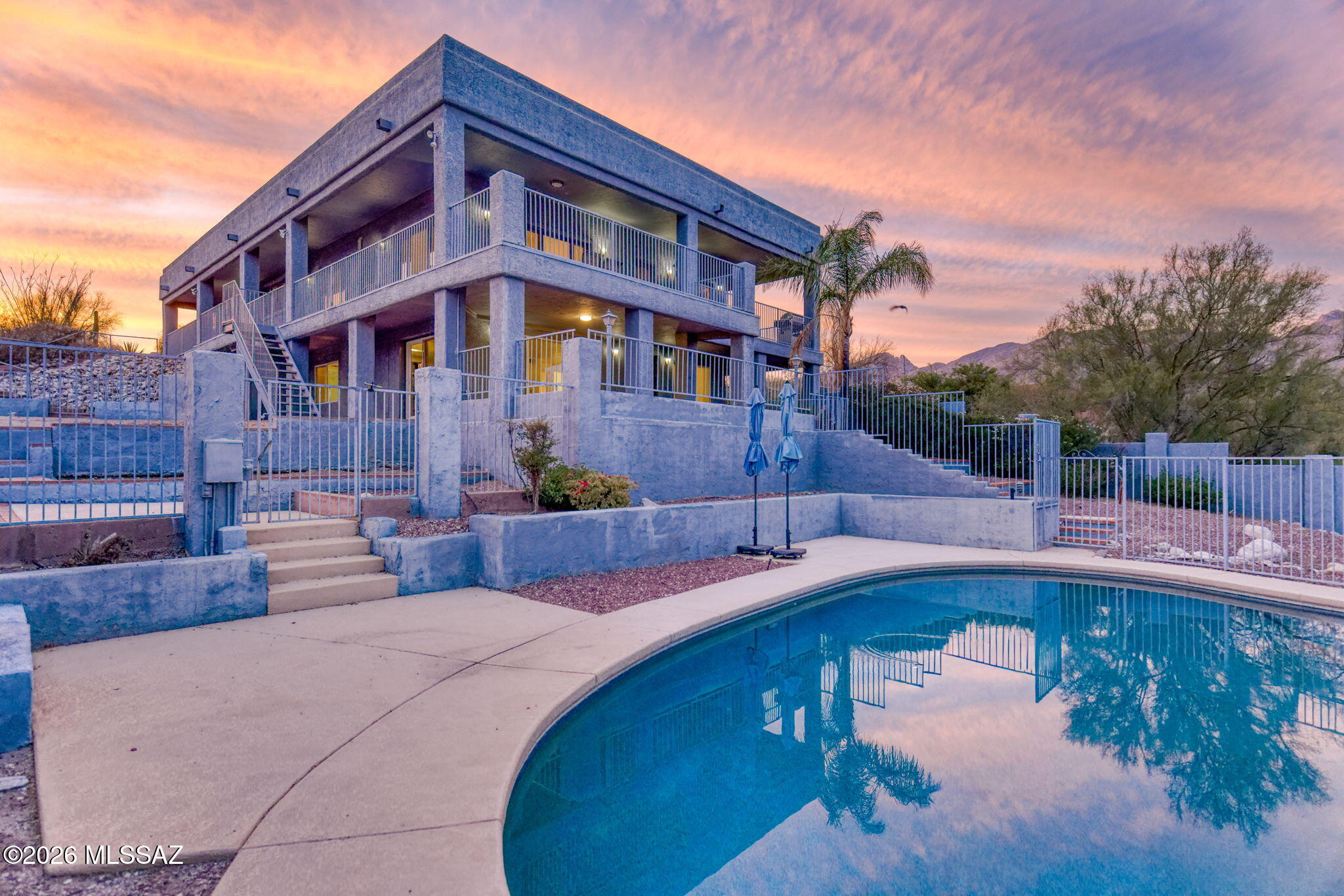 Perched high in the coveted Catalina Foothills, this exceptional 3,500 sq ft residence at 5036 N Calle Bosque is a masterclass in elevated desert luxury, offering sweeping panoramic views of the Santa Catalina Mountains and the sparkling Tucson cityscape below. Set on an expansive 1.02-acre homesite, the property delivers a rare combination of privacy, scale, and architectural sophistication--an increasingly scarce offering in one of Southern Arizona's most prestigious enclaves. Renowned for its stunning natural beauty, upscale homes, and proximity to world-class amenities, the Catalina Foothills is synonymous with luxury living in Tucson. Residents enjoy immediate access to premier golf courses, fine dining, high-end shopping, and scenic hiking trails, all while being just minutes from the city's cultural and business hubs. The area's elevated positioning not only provides cooler temperatures and breathtaking vistas but also reinforces its reputation as one of the most desirable addresses in the region.

From the moment you arrive, the home makes a striking impression. A long, private approach leads to a sophisticated façade defined by clean architectural lines and thoughtfully integrated desert landscaping. Native vegetation and sculpted hardscape design create a seamless connection between the built environment and the surrounding Sonoran Desert.

Inside, the residence unfolds into expansive, light-filled interiors designed to maximize both comfort and visual impact. Walls of glass and strategically placed windows frame the ever-changing desert landscape, capturing vibrant sunsets, rugged mountain contours, and shimmering city lights. The open-concept layout effortlessly blends formal and informal living spaces, creating an ideal setting for both refined entertaining and relaxed everyday living.

The thoughtfully designed floor plan features 4 bedrooms and 3 bathrooms, each space curated with a focus on quality, proportion, and livability. The chef's kitchen anchors the home with premium appliances, custom cabinetry, and a generously scaled island that functions as both a culinary workspace and a social centerpiece.

The main-level primary suite serves as a tranquil sanctuary, offering expansive views, a spa-inspired bathroom, and ample closet space. On the lower level, a second primary ensuite introduces exceptional versatility--perfect for multi-generational living, extended stays, or a private guest retreat that offers independence without compromise. Additional bedrooms provide flexibility for family, guests, or dedicated office space, all appointed with refined finishes.

Outdoor living is equally compelling. Designed to embrace Tucson's year-round sunshine, the property features multiple patios, shaded lounge areas, and a resort-style pool that invites both relaxation and entertaining. Whether hosting sunset gatherings or enjoying quiet mornings overlooking the desert, the outdoor spaces elevate the living experience to a truly resort-caliber standard.

Located within the highly regarded Catalina Foothills School District, the home also benefits from access to some of the area's top educational institutions--further enhancing its long-term value and appeal.

With its generous acreage, architectural presence, and prime foothills location, this residence represents a rare opportunity to own a true desert estate. Sophisticated yet grounded in its natural surroundings, it captures the essence of luxury living in the Catalina Foothills--where privacy, beauty, and lifestyle converge.