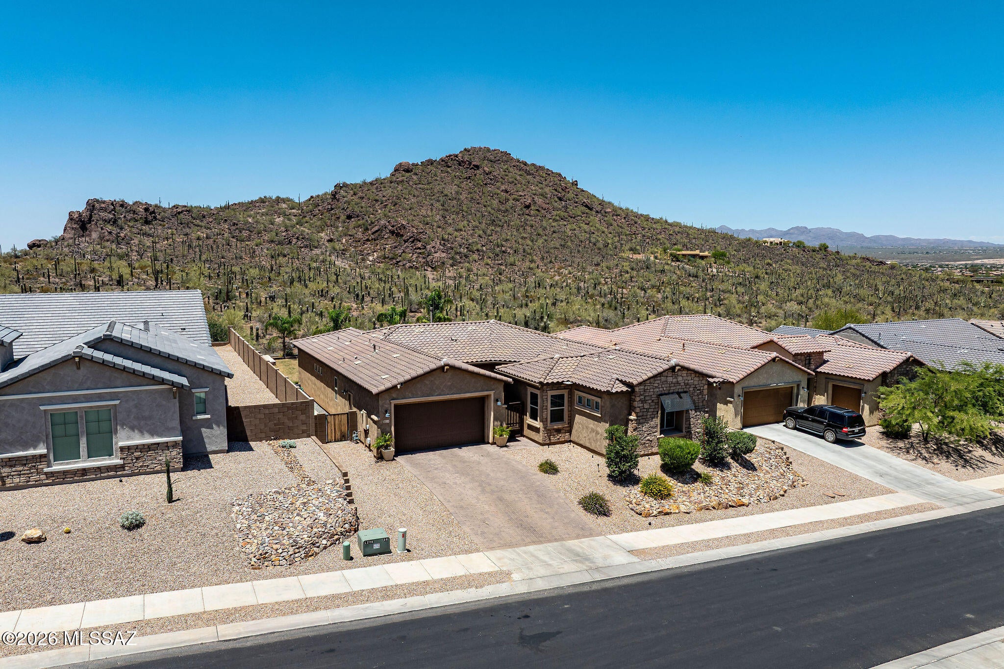 Views, Views, Views! Situated on one of the premier lots in the subdivision, this exceptional home is positioned on a premium ¼ acre cul-de-sac lot with no rear neighbors and breathtaking, unobstructed mountain views. Located within the gated enclave of Lazy K Bar Ranch, bordering the stunning landscapes of Saguaro National Park, this property offers remarkable privacy and tranquility while remaining conveniently close to shopping, dining, schools, and I-10. This newer home is extensively upgraded and showcases custom finishes throughout. A gated courtyard entry with a welcoming sitting area and attractive stone accents creates outstanding curb appeal. Inside, the gourmet kitchen is designed to impress, featuring an abundance of custom cabinetry, an oversized quartz island with seating for five, undermount sink, pendant lighting, and stainless steel appliances including a gas cooktop, decorative hood, built-in convection oven and microwave, dishwasher, and French-door refrigerator.
The luxurious primary suite serves as a private retreat, featuring a huge bedroom with ample space for a sitting area and views of the surrounding mountains. The spa-inspired primary bathroom offers custom vanities with quartz countertops, dual sinks, upgraded designer faucets, and a large walk-in shower with elegant tile surrounds extending to the ceiling, creating a sophisticated and modern atmosphere.
Designed for seamless indoor-outdoor living, the backyard is one of the largest in the community and captures spectacular mountain views and unforgettable Arizona sunsets. Enjoy lush grass, open-view fencing, mature trees and landscaping, stone patios, and a raised deck with a firepit--perfect for entertaining or relaxing under the desert sky. The large covered patio, complete with an impressive eight-blade ceiling fan, provides year-round comfort and enjoyment. Additional features include a spacious walk-in laundry room and flexible living spaces that accommodate a variety of lifestyles. Offering unparalleled views, refined finishes, exceptional outdoor amenities, and an unbeatable location, this remarkable home embodies luxury desert living where beauty, comfort, and convenience come together.