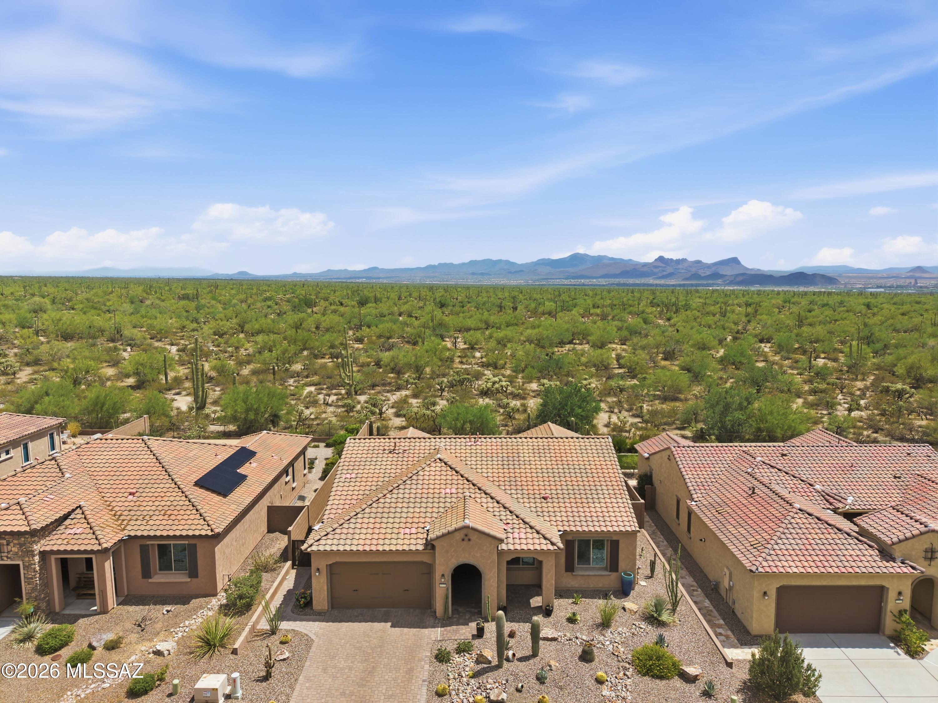 Outstanding views, no neighbors behind! Experience the ultimate blend of modern luxury, poolside mountain views, and dynamic community living in this exceptional residence situated inside Del Webb at Dove Mountain, a 55+ Active Adult community. This beautifully designed Pursuit model, 2BD/2BA+Office/Den (2,103sqft) contemporary home offers premium modern craftsmanship, and a flowing open floor plan with zero interior steps. Pass through the crisp entryway into a massive great room layout illuminated by a series of expansive viewing windows to maximize the stunning mountain views. The interior features a highly sophisticated neutral color scheme accented by a combination of pristine ceramic tile. At the core of the residence is a gourmet kitchen built for effortless entertaining. It is centered around a spacious island with breakfast bar seating, rich custom cabinetry, premium solid granite countertops, and high-end stainless-steel appliances. The intelligent footprint features two large, well-separated bedrooms plus an independent flex den that makes an ideal home office, media hideaway, or creative studio. The primary bedroom retreat provides a comforting personal oasis complete with a vast walk-in shower layout and split vanity configurations. The open-concept layout flows smoothly out to a peaceful, low-maintenance rear yard with a beautiful pool and spa. Fully enclosed by secure block and wrought-iron view fencing, this outdoor sanctuary borders scenic natural desert and mountain views. Whether hosting a weekend barbecue on the deep covered patio or enjoying a quiet morning coffee, the east/west exposure showcases glowing mountain backdrops and beautiful desert landscapes. Living in this community gives you access to Del Webb's world-class community amenities. Residents enjoy a state-of-the-art recreation center featuring a resort-style pool and spa, a fitness pavilion, tennis and pickleball courts, and a network of paved walking trails. Surrounded by scenic foothills and just minutes from the premier resort and spa at The Ritz-Carlton, Dove Mountain, this turn-key property serves as the ideal high-desert retreat. Views!