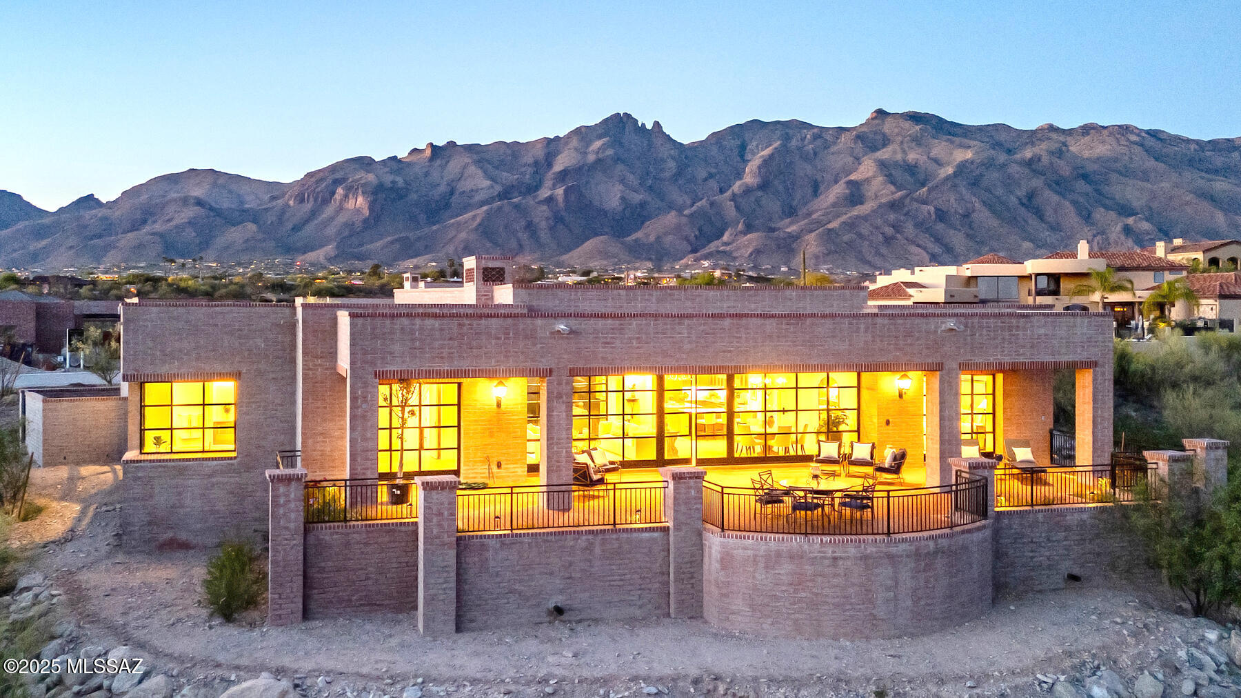 This brand-new, 3,421 sq. ft home is more than a style. Contemporary desert vernacular is an architectural language grounded in place, according to local architectural historian R. Brooks Jeffery, respecting the delicate Sonoran Desert environment, and incorporating time-honored design principles with contemporary interpretations that reflect the cultural characteristics unique to Tucson. Situated on .88 acres at the end of a quiet cul-de-sac in the gated Quintana in the Catalina Foothills, this residence offers unmatched city and mountain views and a level of construction quality rarely seen in today's new builds.

Designed by renowned architect Michael Franks and brought to life by La Quinta Building Company, this 3-bedroom, 3 ½-bath home was built to endure, featuring masonry construction with mortar-washed brick details along with steel casement windows and doors with dual-glazed high-efficiency glass.

Inside, the spacious great room showcases walls of glass, a beamed ceiling, and a carved limestone fireplace, seamlessly blending indoor living with the surrounding desert landscape. Scored, integral-color concrete floors flow throughout the home, complemented by custom alder wood and glass cabinetry and 8-foot solid wood interior doors, every detail carefully chosen to elevate the home beyond standard finishes.

The gourmet kitchen features a generous center island, natural quartzite countertops, and a premium appliance suite including Sub-Zero, Wolf, and Cove.

This home offers two primary suites, each with spa-like en-suites featuring quartzite tub decks, custom limestone tile and glass shower enclosures, and custom-designed walk-in closets with built-in organization.

Additional features include a fully integrated audio, visual, and security system, state-of-the-art mechanical systems and motorized shades in private areas.

Outdoors, a brick driveway and courtyard entry, hand-forged wrought iron gates and railings, and professionally designed hardscape and landscape create a striking first impression. The expansive rear porch captures panoramic views of sparkling city lights and the surrounding mountain ranges.

This single-level home exemplifies architectural integrity and enduring quality, as an extension of its natural surroundings creating harmony between architecture and nature. Located just minutes from premier golf courses, country clubs, and world-class dining and shopping.
