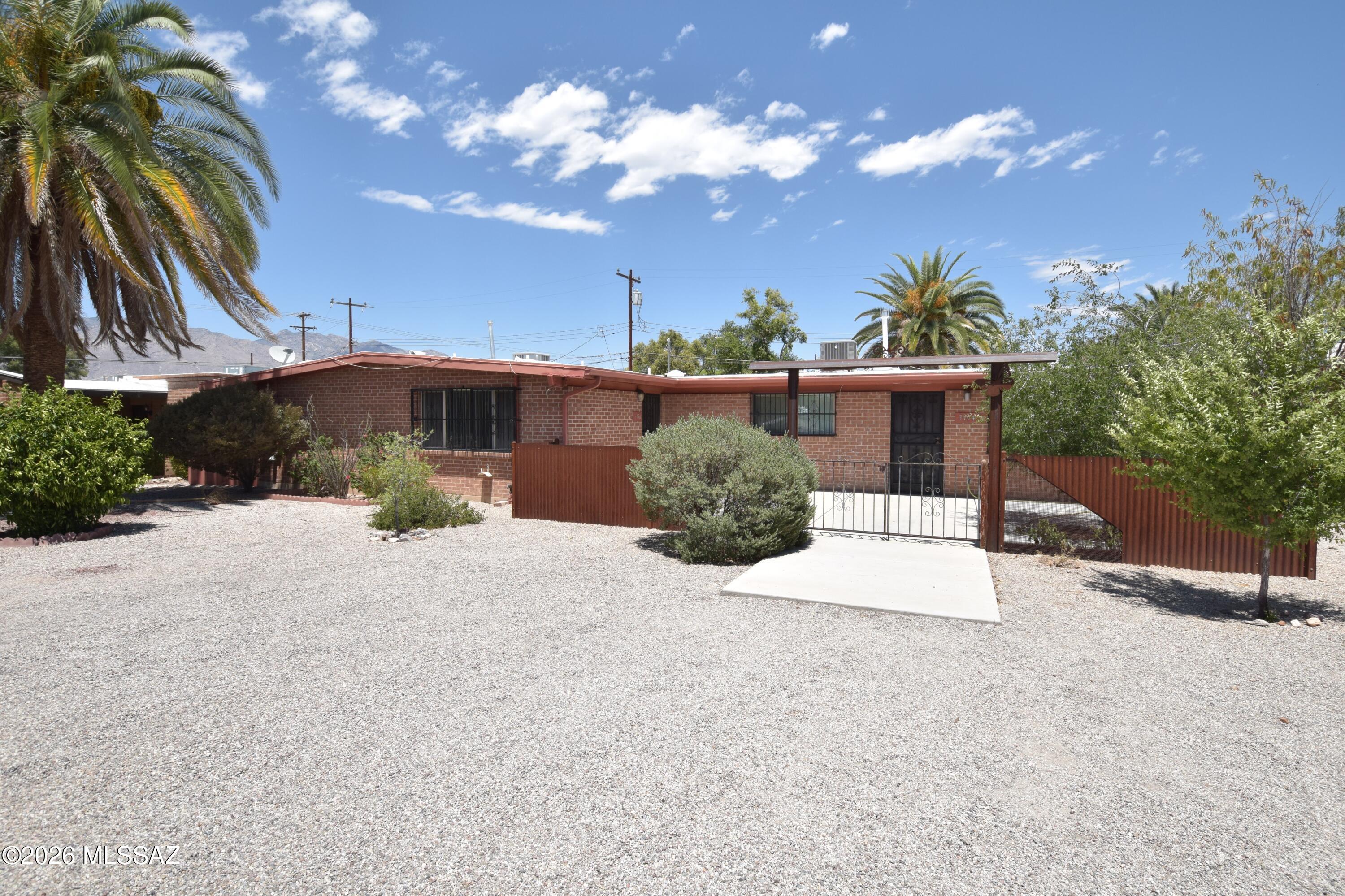 Located in the historic Fort Lowell Estates neighborhood of Central Tucson, this beautiful 3-bedroom, 2-bathroom duplex home spans 1,148 square feet and offers an ideal blend of custom craftsmanship and modern comfort. A welcoming front entry features a charming courtyard highlighted by custom metalwork, leading into an open and bright single-level layout. The interior has durable tile floors throughout and features ceiling fans in all rooms, alongside a central air conditioning and central heating system for year-round climate control. The functional kitchen comes equipped with a sleek stainless steel french door refrigerator and sits conveniently adjacent to dedicated washer and dryer hookups. Outside, residents will enjoy an expansive, fully fenced backyard that wraps around two sides of the building, providing private outdoor space perfect for relaxing. Practical upgrades include one covered parking space with an attached storage unit for your extra gear. This prime midtown location provides quick access to local shopping along Grant & Fort Lowell Road, Tucson Medical Center, and nearby parks like Fort Lowell Park. The property policy considers dogs on a case-by-case basis, though no cats are permitted on the premises. Combining distinct Southwestern curb appeal with central convenience, this move-in-ready property is perfect for anyone seeking effortless Tucson living.