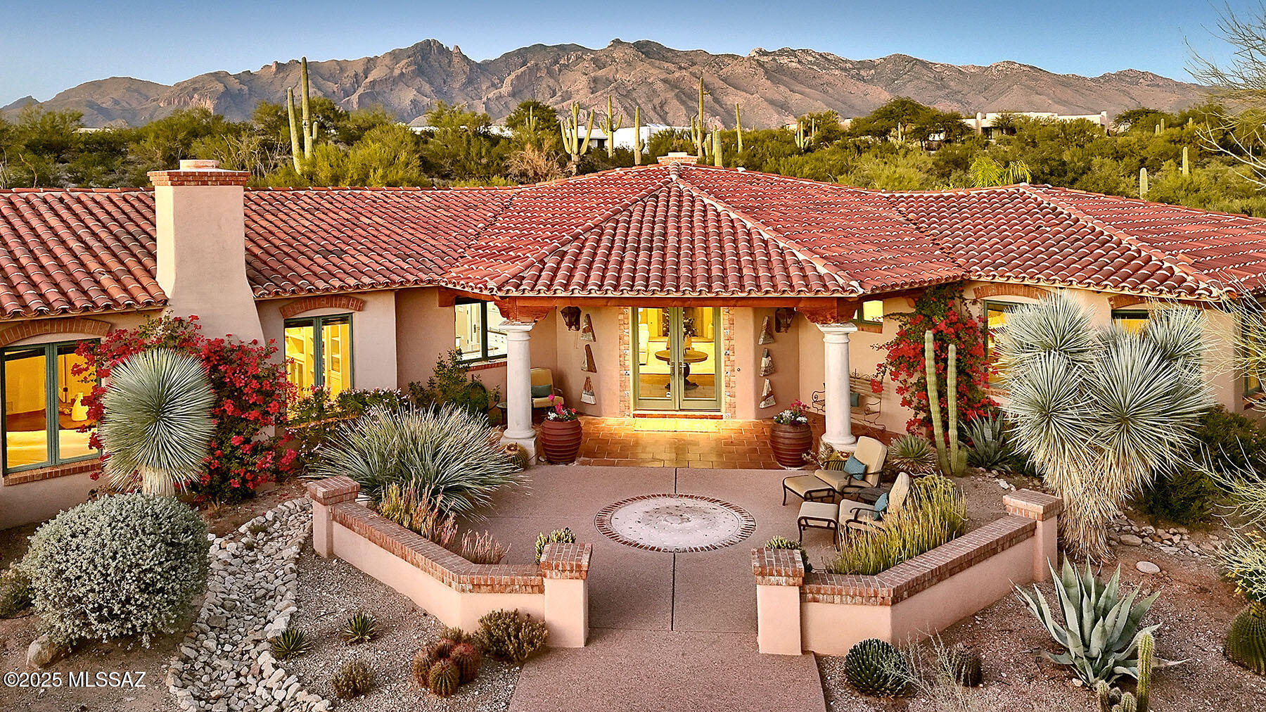 Located in the prestigious, guard-gated Catalina Foothills Estates #10 and sited on a lush 2.19-acre cul-de-sac lot, this 3,771 sq. ft., 3-car garage residence draws inspiration from the timeless charm of a Spanish Hacienda and classic Santa Barbara design. Crafted with exceptional materials and meticulous attention to detail, the home radiates authenticity at every turn, from the welcoming courtyard with fountain, to the all-masonry stucco construction and mission tile roof with chinked mortar.  Inside, the warm and inviting living room features a masonry fireplace, hand-plastered walls, art niches, and rustic ceramic tile flooring. Natural light fills the home through Pella windows and doors.  The chef's kitchen is a true showpiece, offering dual cooking islands, a Viking six-burner range, two Viking ovens, and two dishwashers, ideal for both everyday living and effortless entertaining.  A spacious family room provides a second fireplace, built-in bookcases, and integrated surround sound. The gracious primary suite serves as a luxurious retreat with a beautifully designed bathroom and a private sitting room perfect for quiet relaxation.  Outdoors, the property unfolds into beautifully landscaped grounds featuring native stone walls, mature desert vegetation, a sparkling swimming pool, and winding walkways, an idyllic setting that captures the serenity and natural beauty of desert living at its finest.  See to appreciate.