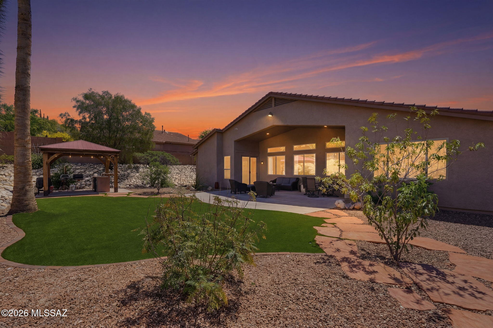 Immaculately maintained and beautifully appointed, this 2,472 sqft home in desirable gated Rancho Cancion community offers flexible living with high ceilings and lots of natural light. The updated chef's kitchen features a high-end Thermador Pro gas range, Quartz countertops, breakfast bar, conversation island, and pantry. This split bedroom plan includes 3 bedrooms plus den/office/4th bedroom. The primary suite offers a luxurious bath with heated floors, extended shower, dual sinks, granite counters, and walk-in closet plus direct patio access to the north-facing, tiered backyard with pergola kitchen area, turf grass, firepit, citrus tree, and flagstone paths. Owned solar, newer roof, water harvesting system, and 3-car garage complete this .37-acre gem near Saguaro National Monument East. THE PROPERTY
> Desirable Gated Rancho Cancion Neighborhood
> .37-acre Parcel 
> Minutes from Saguaro National Monument East
> North-Facing Enclosed Backyard
> Pergola Outdoor Kitchen Area
> Low-care Landscaping with Mature Vegetation, and Irrigation
> Water Harvesting System
> Turf Grass
> Tiered Backyard with Sitting Areas and Firepit
> Flagstone Walkways
> Tangerine Citrus Tree

THE HOME 
> Immaculately Maintained
> 2472 Square Feet of Living Area
> Flexible Space with Living and Dining Room Combination and Family Room Off Kitchen or as currently being used with Large Living Room and separate Dining Room
> High Ceilings with Lots of Windows
> Updated Chef's Kitchen with High-End Thermador Pro Natural Gas Range, Full Size Side-By-Side Refrigerator/Freezer unit, Quartz Countertops, Breakfast Bar, Conversation Island, and Pantry Closet
> Split Bedroom Plan
> 3 Bedrooms plus Den/Office/4th Bedroom
> Primary Bedroom Suite has Direct Access to Covered Patio and Backyard
> 2 Bathrooms
> Spacious Primary Bathroom has Heated Floors, a Custom Extended Shower, Dual Sinks, Granite Countertops, and a Large Walk-in Closet
> Guest Bathroom has Dual Sinks, Tub/Shower Combo and Granite Countertops
> Shade Screen at Front Entrance
> Front Door Keypad Locking System 
> Covered Patio
> Spacious 3-Car Attached Garage 
> Owned Solar Electric System
> Water Softener & Reverse Osmosis
> Newer Roof