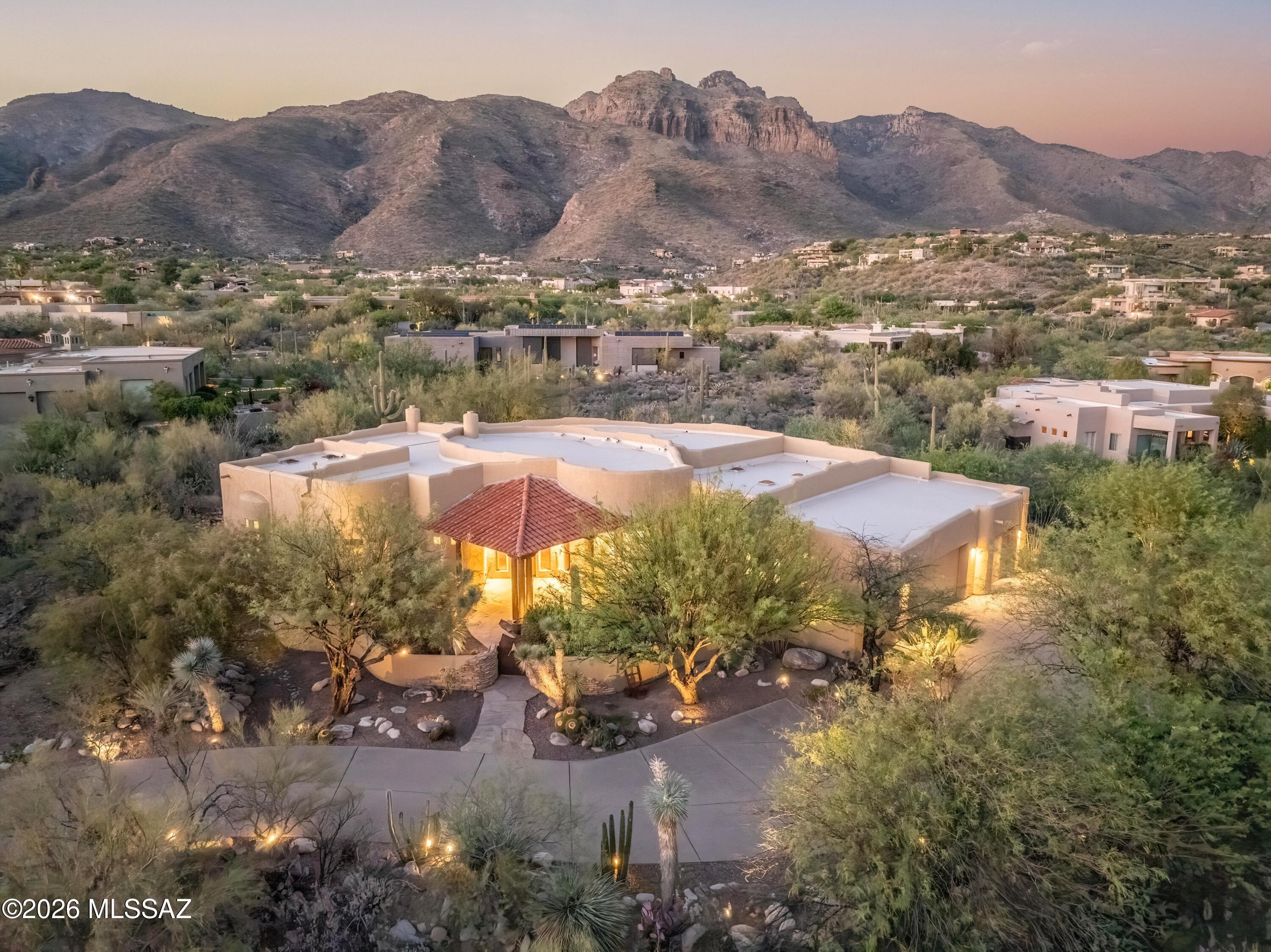 Experience the BEST of Arizona luxury living in the exclusive gated enclave of Pima Canyon. Recently refreshed with new exterior paint and perfectly positioned to capture breathtaking mountain views, this exceptional residence offers an unparalleled blend of
elegance, comfort, and privacy. A beautifully landscaped courtyard with custom mesquite gate welcomes you into a home where soaring ceilings, walls of windows, and abundant natural light create an atmosphere of sophistication and warmth. Designed to showcase the surrounding Catalina Mountain vistas and lush desert landscape, the expansive open-concept floor plan seamlessly connects formal and casual living
spaces, making it ideal for both intimate gatherings and grand entertaining. At the heart of the home, the gourmet chef's kitchen is a true showpiece, featuring professional-grade stainless steel appliances, rich custom cabinetry, granite countertops, an
expansive walk-in pantry, and a generous center island that naturally becomes the gathering place for family and guests alike. Adjacent dining and living areas flow effortlessly to the resort-style backyard, creating the perfect indoor-outdoor living
experience. Flow outside to your private desert retreat where stunning mountain views provide a spectacular backdrop to the sparkling pool, soothing spa, tranquil waterfall, and covered patio. Whether enjoying Arizona's endless sunshine, entertaining guests,
or unwinding beneath the stars, this outdoor sanctuary offers the ultimate setting for relaxation. The thoughtfully designed split floor plan provides exceptional privacy and flexibility. The luxurious primary suite serves as a peaceful retreat, complete with its own fireplace, spacious sitting area, spa-inspired bath, soaking tub, and oversized walk-in closet. Two guest bedrooms are situated in separate wings, each featuring an en-suite
baths, while an additional bedroom or study offers versatility for today's lifestyle. From the dramatic great room with 14-foot ceilings and a statement fireplace to the exquisite finishes, travertine flooring, and timeless Southwestern Contemporary architecture, every detail reflects quality craftsmanship and refined design. Offering a rare combination of luxury, privacy, and natural beauty, this remarkable Pima Canyon Estate embodies the very best of Tucson living.