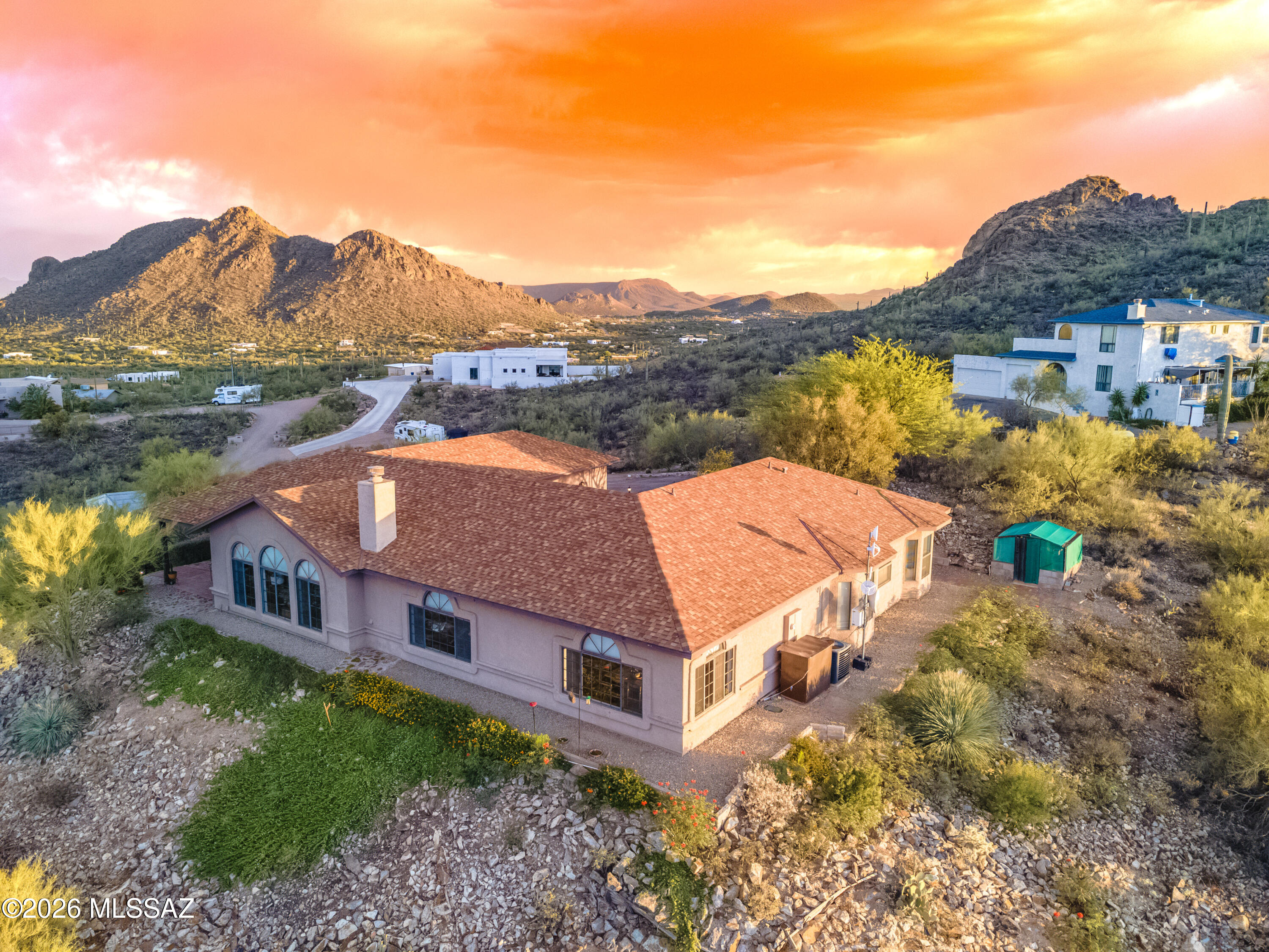 Nestled atop a hill overlooking Tucson Mountain Park, you'll find a peaceful, hacienda-style retreat. With two bedroom wings, each boasting their own entrance, you'll have room for everyone. A separate 2-car garage & storage building at the bottom of the hill has space for all your extras. Fall in love w/ the Sonoran Desert as you admire wildlife, vegetation & incredible sunsets from the serenity of your courtyard, & enjoy Tucson's twinkling city lights from atop your hillside perch. Inside, enjoy immaculately cared for spaces. Cozy up in the family room next to the wood-burning fireplace or relax & unwind in the separate living room. You'll be delighted to watch feathered friends or spectacular sunrises from your dining table. For outdoor enthusiasts, Bittersweet Trail is steps away.