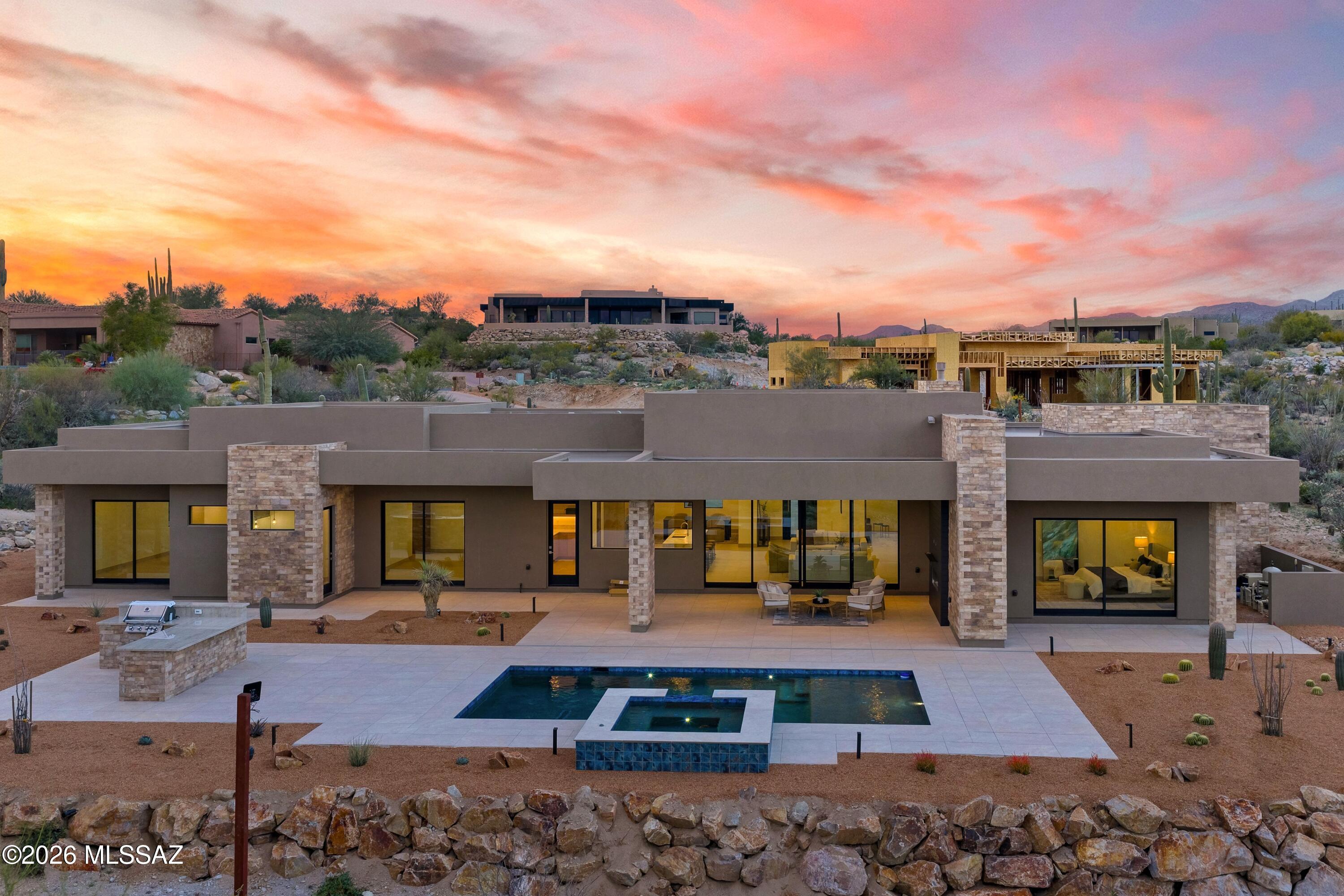 Contemporary architecture, uncompromising views, and elevated finishes define this new custom home in Stone Canyon. This home offers an exceptional opportunity to secure a brand-new, thoughtfully designed property in one of Southern Arizona's most prestigious private golf communities. Be sure to view the construction-progress video included in the listing.

Positioned on an East-facing site with beauitul Catalina Mountain views, the home is approached by a long paved driveway that leads to a striking custom metal-and-glass pivot door. Inside, a full wall of glass frames the dramatic mountain backdrop and floods the open kitchen and great room with natural light.