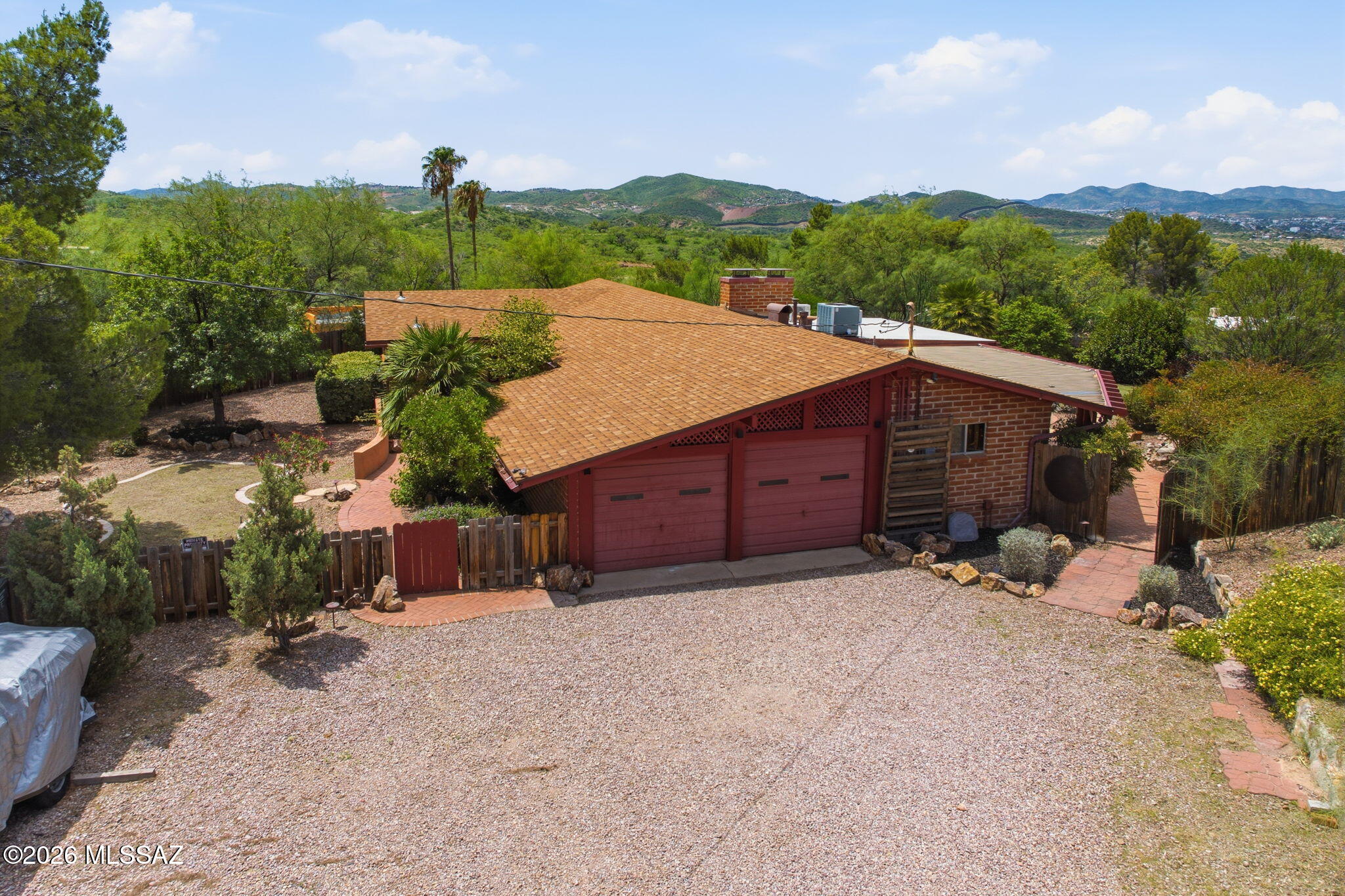 Perched on a hillside in Nogales East, this well-kept 1967 brick home sits on a 1.23-acre lot with superior views. Effortless indoor-outdoor living begins at the paver courtyard with integrated planters, leading to bright, open spaces framed by large windows. The entertainer's dream continues in the spacious glass-enclosed Arizona room overlooking the garden and opening to a covered patio, private areas and water feature. A chef-ready kitchen features under-cabinet LED lighting, wet bar/prep sink. Comfort and charm abound with two wood-burning fireplaces, a bonus room, and professionally planned desert landscape with sprinkler system. Thoughtful landscaping blends with the natural Nogales hillside for a private, serene setting designed for gathering.
