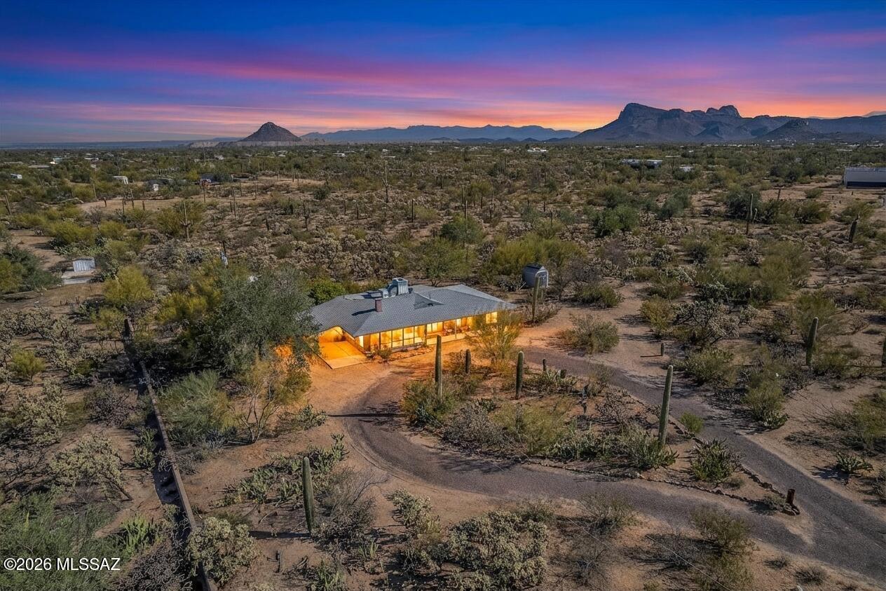 Discover the charm and versatility of this unique property. Featuring beautiful exposed adobe walls, warm wood ceilings, and cozy wood-burning stoves/fireplaces, the home blends rustic character with comfortable living. Enjoy peaceful desert living from the screened-in patio or the nearly complete wraparound porch, perfectly positioned to take in stunning sunrise and sunset views. Most windows are fitted with shutters, and a large picture window in the bedroom captures the surrounding landscape. Over 4 acres! Horse property. Incredible flexibility, ideal as an Airbnb or income-producing rental, or build your dream home and use the existing residence as a guest house or casita. Across from Saguaro National Park. 2 year old HVAC and water heater. A rare opportunity with endless potential!