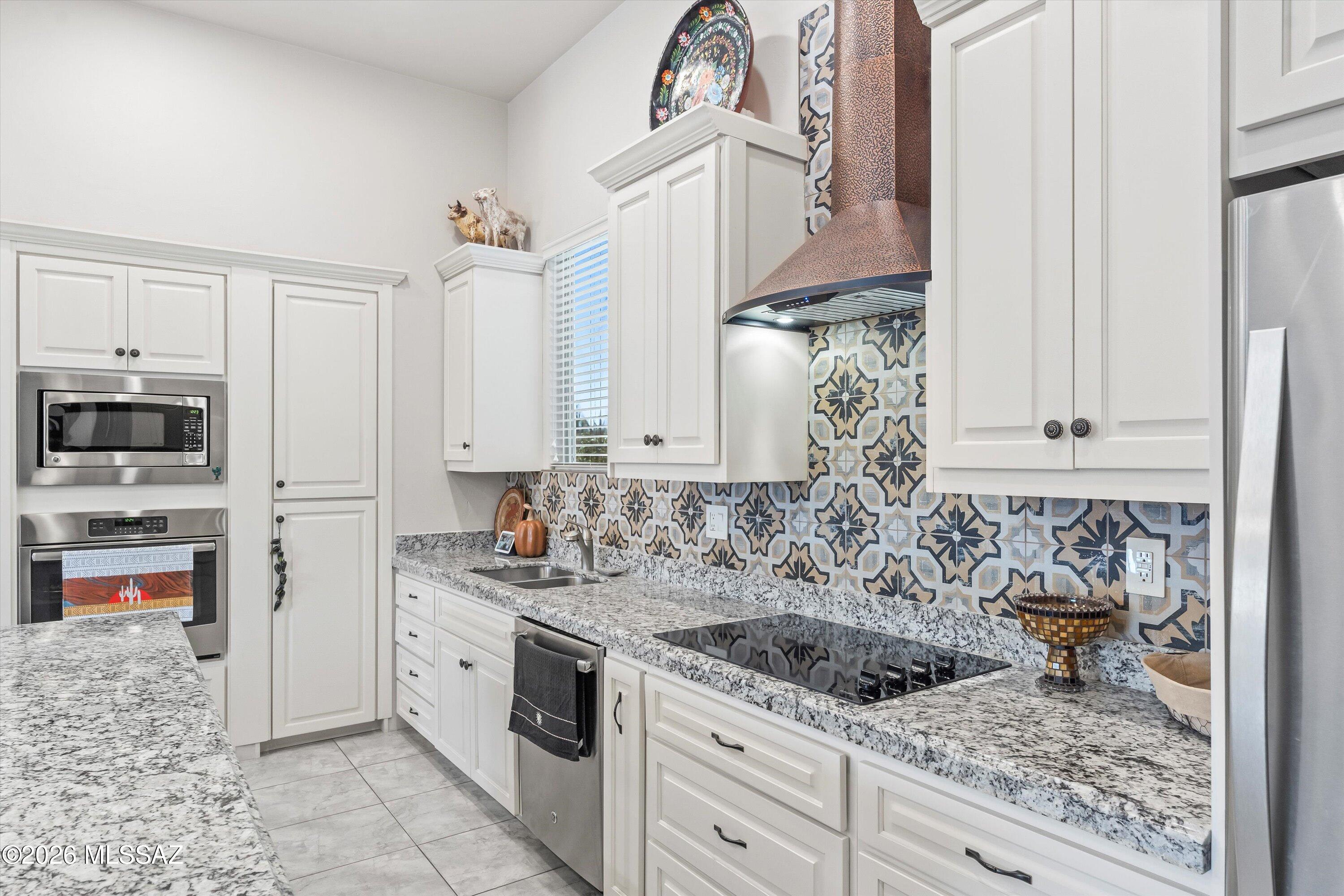 Set on a full acre in Catalina Foothills Estates No. 2 with no HOA, this newer, design-forward residence offers a rare blend of architectural presence, thoughtful layout, and refined finishes. The home features four bedrooms, three bathrooms, 2,243 sq ft, and a well-executed split-bedroom floor plan, providing separation between living and sleeping spaces while maintaining an open, connected flow.
Dramatic barrel-vault and tray ceilings, clean architectural lines, and expansive windows fill the interior with natural light and frame Arizona's ever-changing desert skies. At the center of the home, the chef's kitchen makes a statement with premium white cabinetry, granite countertops with striking veining, stainless steel appliances, and a signature copper range hood framed by artisan tile. Designed for both everyday living and entertaining, the kitchen opens seamlessly to the great room, where a fireplace-centered living space anchors the home and creates an inviting setting for gathering.
The primary suite is positioned separately from the secondary bedrooms and offers a calming retreat with layered tray ceilings, custom millwork, and a spa-inspired bath featuring a soaking tub, dual vanities, designer tile, and a walk-in shower. Additional bedrooms are generously sized and finished with consistent attention to detail, allowing flexibility for guests, home office use, or multi-purpose living.
Outdoor living is equally intentional, with multiple defined spaces including a gated courtyard with pergola and low-maintenance turf. Professionally designed xeriscaping with mature saguaro and desert plantings blends the home seamlessly into its Sonoran Desert setting. From sunrise to sunset, the exterior captures the open skies and desert light that define Foothills living, offering a sense of space, openness, and flexibility rarely found in this setting.
A three-car garage and balanced floor plan complete the property.
The location offers convenient access to Foothills hiking and outdoor recreation, nearby golf courses, and premier shopping and dining destinations including La Encantada and St. Philips Plaza, while remaining immersed in the natural beauty of the Sonoran Desert.