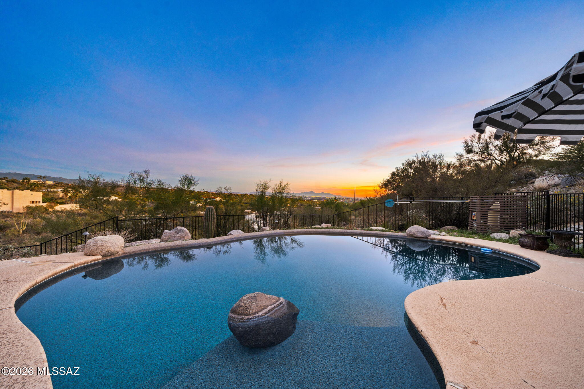 Renovated Foothills residence on 2 acres offering panoramic mountain and city views and exceptional privacy. Set within a well maintained community with HOA supported roving patrol services for added peace of mind, this updated home is just minutes from restaurants, shopping, and everyday amenities.

Outdoor living is the star, with a private pool overlooking sweeping mountain and city vistas and a custom pergola that elevates the entertaining space. A courtyard addition with drainage system, custom ironwork, upgraded exterior lighting, and a new garage door enhance function and curb appeal. The exterior was recently painted, and the HVAC system was replaced about six months ago, providing immediate peace of mind. 
Inside, the home is thoughtfully updated with wide plank flooring, fresh nterior paint, updated lighting, and crisp trim details throughout. The living room is anchored by a fireplace, creating a warm focal point, while a custom iron staircase adds architectural character and refinement.
The primary suite features custom built ins, a spacious walk in closet, and a remodeled bath with solid wood shaker cabinetry with soft close construction, quartz countertops, updated fixtures, and designer lighting.
Energy efficient improvements include multiple Low E window replacements, Milgard windows, and a new sliding glass door in the primary suite. Additional upgrades include refreshed cabinetry in all three bathrooms, relocated laundry with utility sink, sewer line inspection and maintenance, and an oversized ceiling fan in the primary bedroom.
With expansive acreage, panoramic views from the pool and living spaces, and extensive renovations throughout, this home delivers the rare combination of privacy, comfort, and convenience in one of Tucson's most sought after Foothills settings.