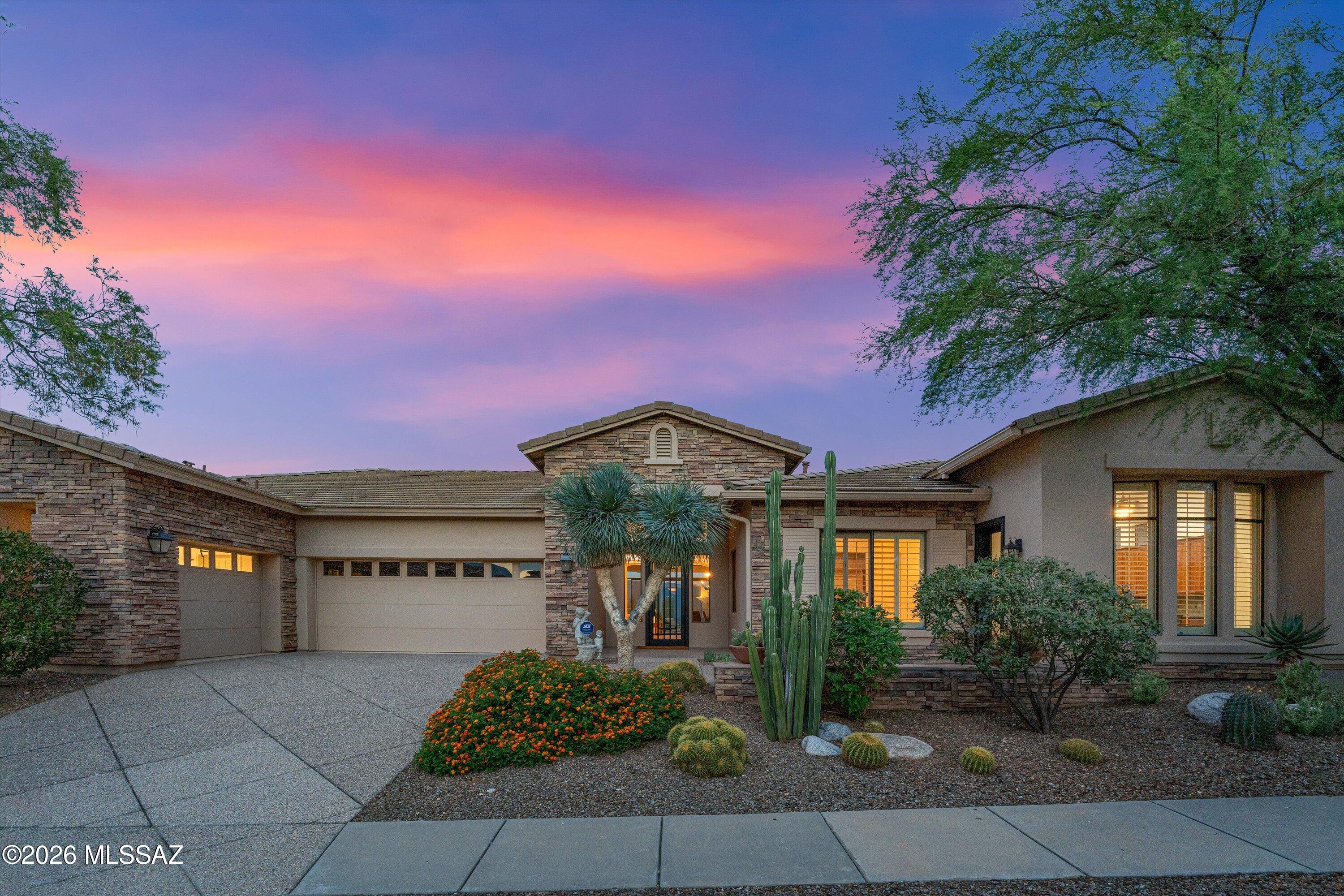 Set against a dramatic backdrop of the Santa Catalina and Rincon Mountains, this contemporary stone-accented residence in Sabino Mountain is defined by its extraordinary, unobstructed views--capturing sweeping desert ranges, glowing sky colors, and distant city lights. Sited high on an exclusive ridgeline in a premier gated enclave, the setting offers a constant connection to Tucson's natural landscape and true Foothills vistas.
Inside, beautifully scaled single-level interiors are filled with natural light, with expansive walls of glass framing the surrounding scenery as a constant focal point. Upon entry through a custom iron-and-glass front door, you are greeted by high ceilings and an elegant formal living and dining space framing immediate desert panoramas. The floor plan flows effortlessly into a gourmet kitchen featuring thick granite surfaces, warm rich cabinetry, gas cooking, an oversized gathering island, and plantation shutters that add timeless refinement.
The residence offers a versatile three-bedroom, three-bath floor plan thoughtfully planned with a flexible den that easily converts into a fourth bedroom. The primary suite is a serene private hideaway, outfitted with an elevated soaking tub, dual vanities, and a custom walk-in closet. Ample built-in storage is found throughout the home, complemented by a spacious three-car garage with substantial storage capacity.
Outdoor living is thoughtfully designed to embrace the resort-caliber scenery. Anchored by an east-facing back patio and pristine PebbleTec spa, it serves as the ultimate vantage point to watch the evening clouds and mountain peaks glow with the dramatic, shifting colors of the desert sunset. Located within gated Sabino Mountain, residents enjoy quiet solitude, scenic privacy, and close proximity to Ventana Canyon Country Club, Sabino Canyon, and top-rated dining.