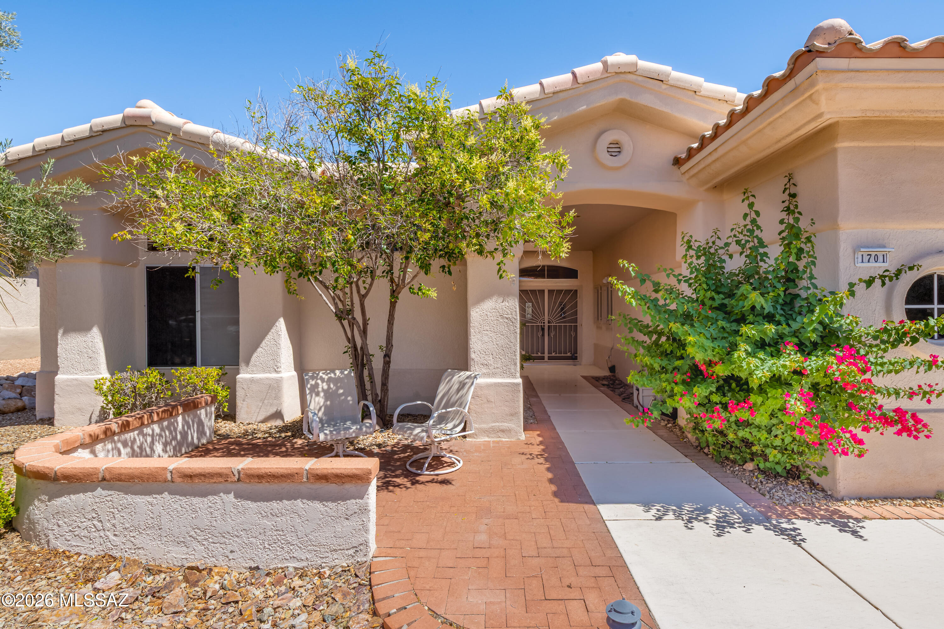 Beautifully positioned on a premium lot backing to natural open space in highly desirable Sun City Oro Valley, this expanded 2,018SF 3BR/2.5BA Sunrise model captures tranquil desert and mountain views while offering spacious indoor/outdoor living designed for Arizona's spectacular sunsets and year-round lifestyle. Walls of windows, soaring ceilings, transom windows, and abundant natural light create a bright, airy atmosphere throughout the thoughtfully designed floor plan. Elegant architectural details including arched openings, art niches, built-ins, and expansive living spaces add warmth and character to the home. The spacious living and dining areas flow seamlessly to the inviting rear patio, while the comfortable family room serves as the heart of the home featuring a cozy fireplace, media niche, display shelving, and large picture windows overlooking the natural desert backdrop. The kitchen offers generous cabinetry, abundant prep space, breakfast bar seating, wall oven, built-in desk/workstation, casual dining area, and an ideal layout for both entertaining and everyday living. Neutral finishes, tile flooring, and durable laminate flooring provide low-maintenance comfort throughout much of the home. The oversized primary suite is a relaxing retreat featuring large windows framing peaceful desert views, private patio access, spa-inspired bath with dual vanities, soaking tub, separate shower, makeup area, and an exceptionally large customized walk-in closet with extensive built-ins and storage. Two additional bedrooms provide flexibility for guests, hobbies, or home office space. Additional highlights include an expanded utility/storage room, powder room, ample storage throughout, and oversized 2.5-car garage with golf cart storage potential and built-in cabinetry. Enjoy the exceptional amenities of Sun City Oro Valley including golf, fitness center, swimming, pickleball, tennis, walking trails, restaurants, social clubs, and countless recreational activities. Conveniently located near shopping, dining, medical facilities, Catalina State Park, hiking trails, and the Oro Valley Community Center.