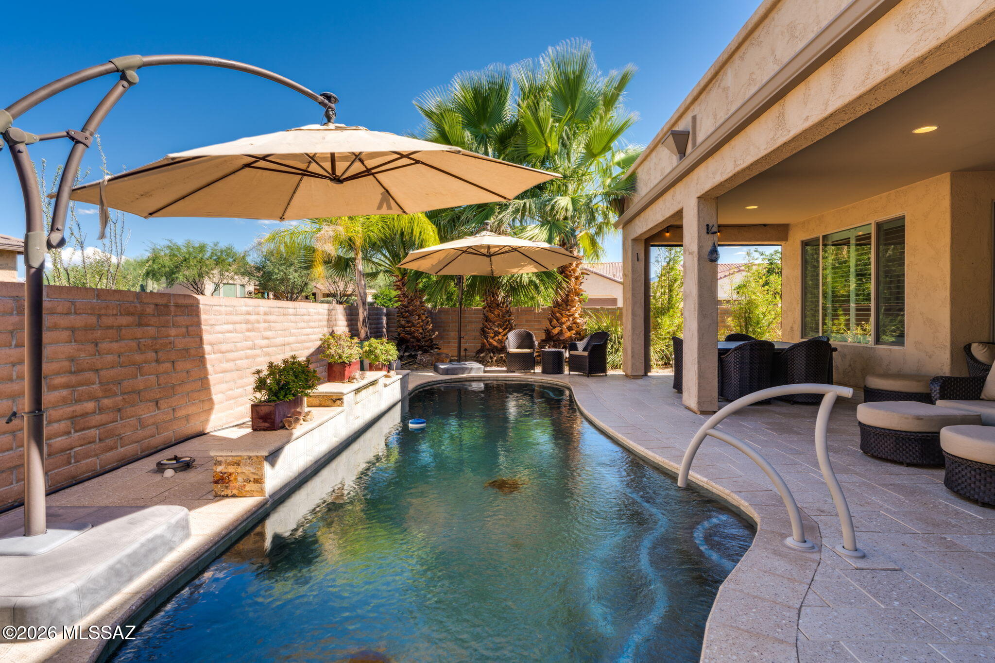 Exceptional Pavona in Quail Creek featuring sophisticated finishes and a spectacular resort-style backyard! The open-concept living, kitchen and dining areas showcase soaring 11' ceilings, neutral tile and beautiful pool views. Gourmet kitchen offers a grand island, quartz counters, tile backsplash, GE Profile appliances, butler pantry, walk-in pantry and built-in bar. Spacious primary suite includes dual vanities, soaking tub, large walk-in tile shower and custom closet. Enjoy the private backyard with heated pool, Bullfrog hot tub, mature palms and citrus trees, outdoor kitchen with gas grill, and 401 sq. ft. covered patio with dry bar, mini fridge and TV mounts. 27 owned solar panels complete this exceptional Arizona retreat!