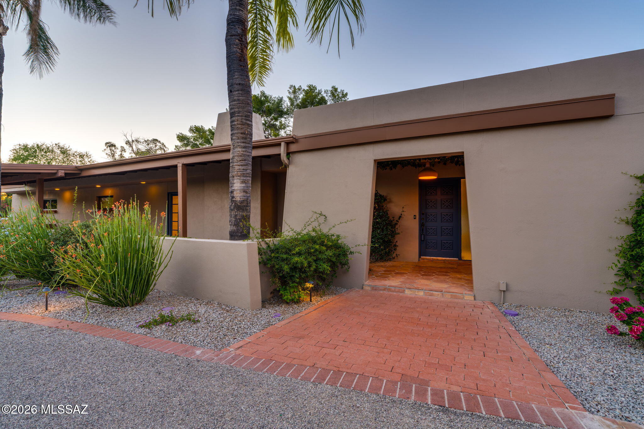 Set on a lush and private .78-acre lot in TUCSON COUNTRY CLUB, this classic 1960s ranch offers a refreshing blend of timeless architecture, comfortable living spaces, and thoughtful updates. Surrounded by mature vegetation and framed by a welcoming front porch, the home reflects the relaxed character and enduring appeal that have made this one of Tucson's most sought-after neighborhoods. Inside, natural light fills the home, while French doors opening to both front and back patios create an easy connection to the outdoors. Light-stained concrete flooring adds a clean, contemporary touch, complementing the home's original character. The split floor plan includes four bedrooms, including two primary suites that provide flexibility for guests, extended family, or changing needs over time... The living room centers around an original stone fireplace and flows seamlessly into the dining area, where built-ins and a large picture window add both charm and function. The kitchen opens to a comfortable family room with a second fireplace, creating multiple spaces to gather, relax, or entertain. A third fireplace anchors the main primary suite, offering a quiet retreat at the end of the day. A separate den or office provides additional flexibility and space for storage, hobbies or projects, while the garage offers plenty of storage and workspace. Outdoors, the walled-in pool and expansive north-facing backyard provide room to enjoy Tucson's year-round sunshine, whether hosting friends, gardening, playing, or simply unwinding in a peaceful setting. Beyond the property itself, Tucson Country Club offers a lifestyle rooted in community, tradition, and recreation. Behind the manned gates, residents enjoy tree-lined streets, mature landscapes, and convenient access to golf, tennis, pickleball, swimming, dining, shopping, and everyday amenities. It is a neighborhood that feels established and welcoming, offering a rare combination of privacy, character, and connection to the best of Tucson living!