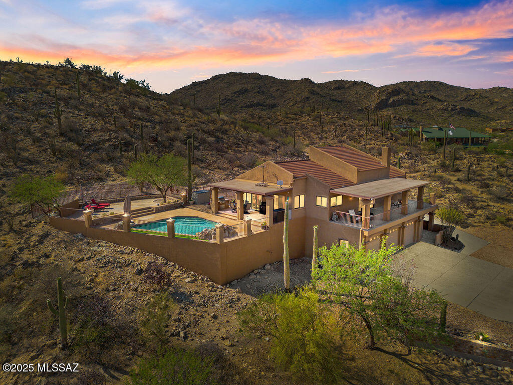 This 4.25 acre, gated, 2 story home in the Tortolita Mountains is private and peaceful offering 3-bed, 2-bath escape with a 2 well-share, owned commercial grade 12kW solar system (separate structure-not on roof) and 150-gallon propane tank and an extended 27' deep x 38' wide 3 car garage. This 2,124 sq ft home embraces it's mountain setting with panoramic views. Recently added wood-like tile throughout excluding bedrooms. Remodeled bathrooms with quartz countertop and stunning tiled walk-in showers.  The living areas are elevated on the second floor and surrounded by balconies. Vaulted ceilings and an open layout creates a bright, airy atmosphere with seamless indoor-outdoor flow. This is one you must see in person. 2.5% assumable VA loan for qualified vets.