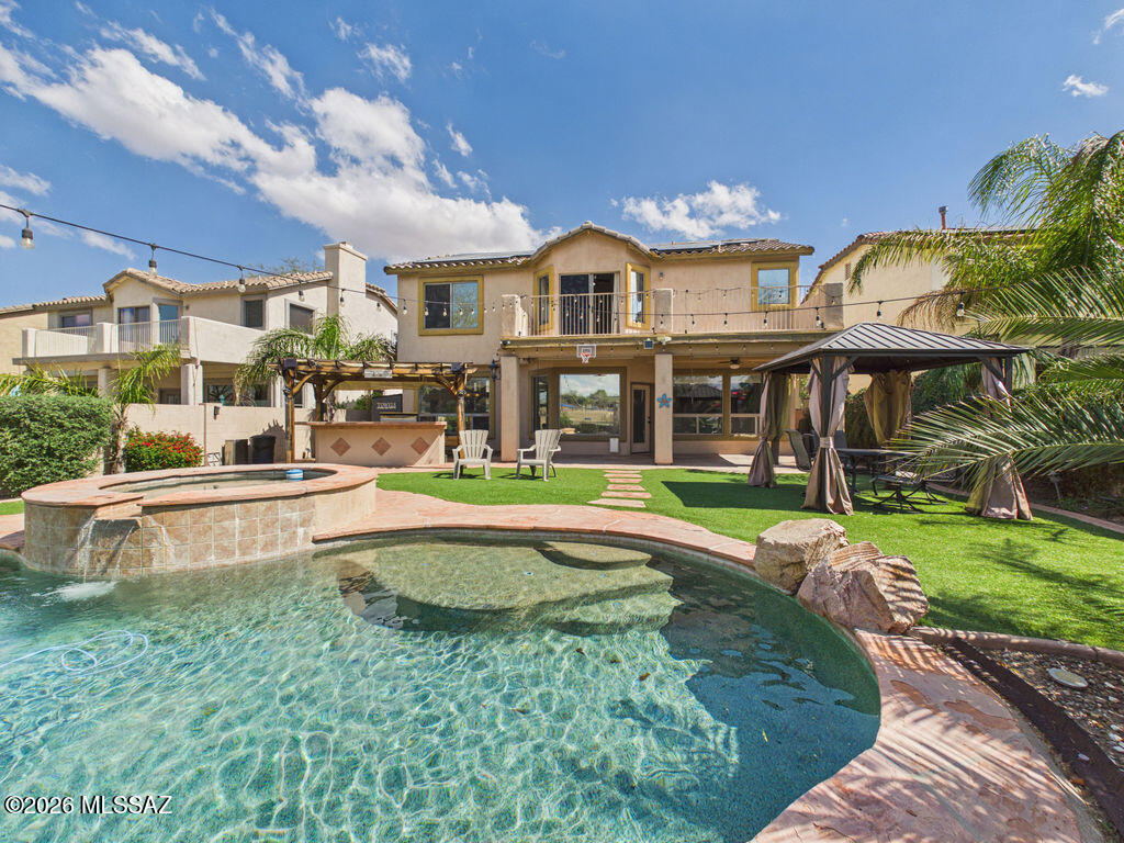 Living at 15384 S Camino Agua Azul places you in one of the most amenity-rich communities in southern Arizona. Located within the gated Agua Azul section of Rancho Sahuarita, the neighborhood blends scenic lake views with a community environment designed for recreation, outdoor activity, and connection. This two-story lakefront home offers 2,619 square feet with four bedrooms and two and a half bathrooms. The home features soaring ceilings and a layout designed for everyday living and entertaining. The kitchen includes granite countertops and stainless steel appliances. Upstairs, the primary suite includes a flexible sitting room, loft, or office space and a balcony overlooking the lake. Outdoor living takes center stage with a \ covered porch, sparkling pebble-finish pool and spa, outdoor kitchen area, ramada and synthetic turf creating a low-maintenance yard with water views. Additional highlights include a two-car garage with epoxy coating and a dedicated storage area. Conveniently located near the many amenities of Rancho Sahuarita, including parks, recreation facilities, walking paths, and community gathering spaces, all within a gated neighborhood setting.