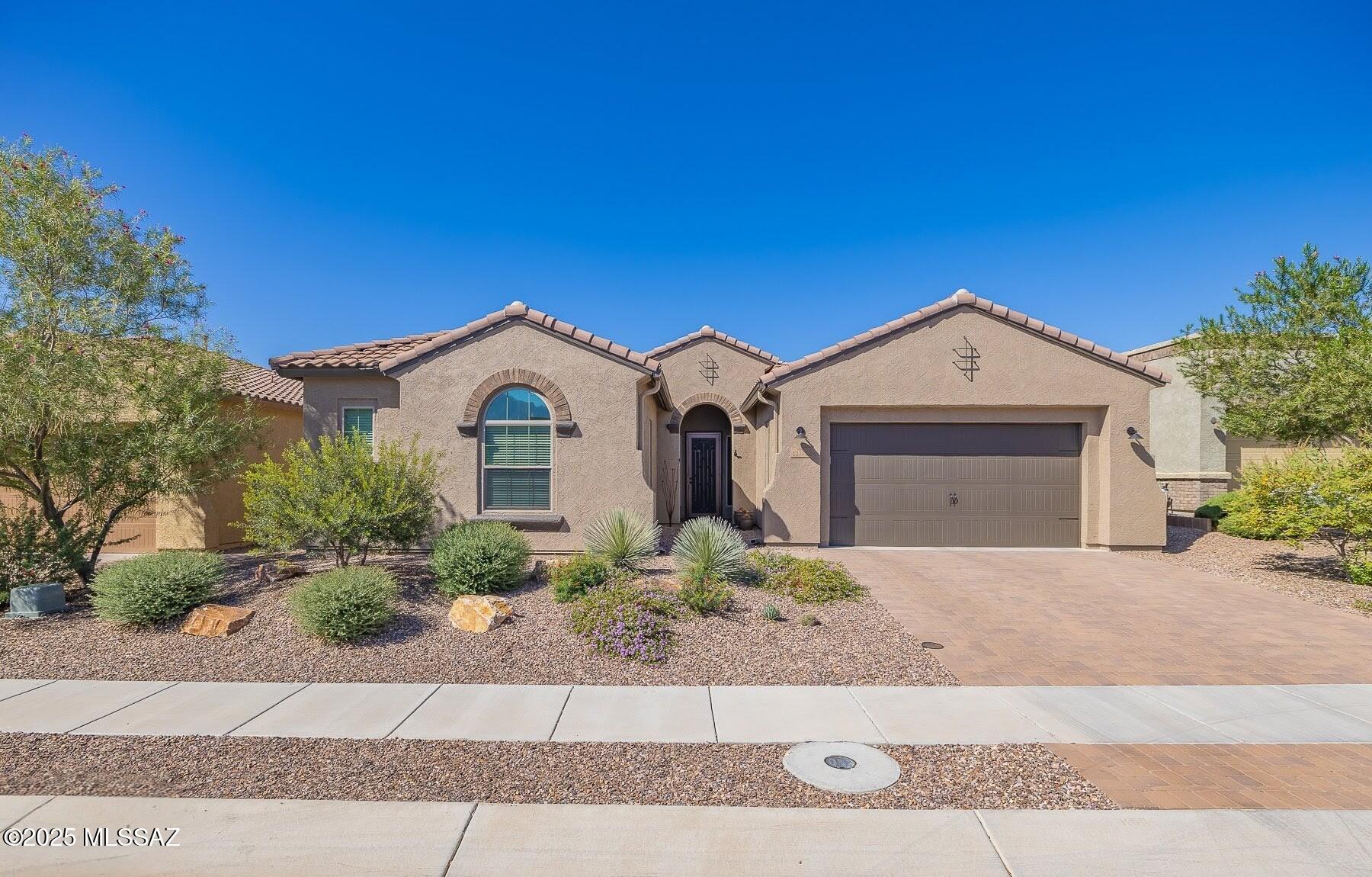 Discover your serene Sonoran Desert sanctuary in gated Alterra at Vistoso Trails. Imagine morning coffee on the covered patio, shaded by a rolling sunshade, overlooking a low-maintenance oasis with Bocce court, hot tub, citrus trees, and desert oaks--perfect for quiet relaxation or lively gatherings. Step inside this elegant Patina model (3BD/2.5BA + den, 2,336 sq ft & tandem 3-car garage) where open-concept living flows effortlessly: a sunlit great room and gourmet kitchen invite leisurely weekends cooking on the 5-burner gas cooktop, or hosting friends around the island breakfast bar. Retreat to the spacious primary suite for ultimate calm--dual vanities, deep soaking tub & expansive walk-in shower. Split bedrooms offer privacy, with a Jack-and-Jill bath and convenient powder room. Modern upgrades enhance effortless living: fresh exterior paint, premium leathered granite, new appliances (2024 oven/microwave), luxury tile and carpet, EV charging, smart garage, security system, 3-zone HVAC, whole-home water softening and outdoor pad with 220V electric for a hot tub. Nestled in Oro Valley's active lifestyle community near Vistoso Trails Nature Preserve trails, Catalina Mountain views, Honeybee Canyon hikes, and local dining--ideal for nature lovers seeking tranquility with easy access to adventure. This home awaits your cherished memories.