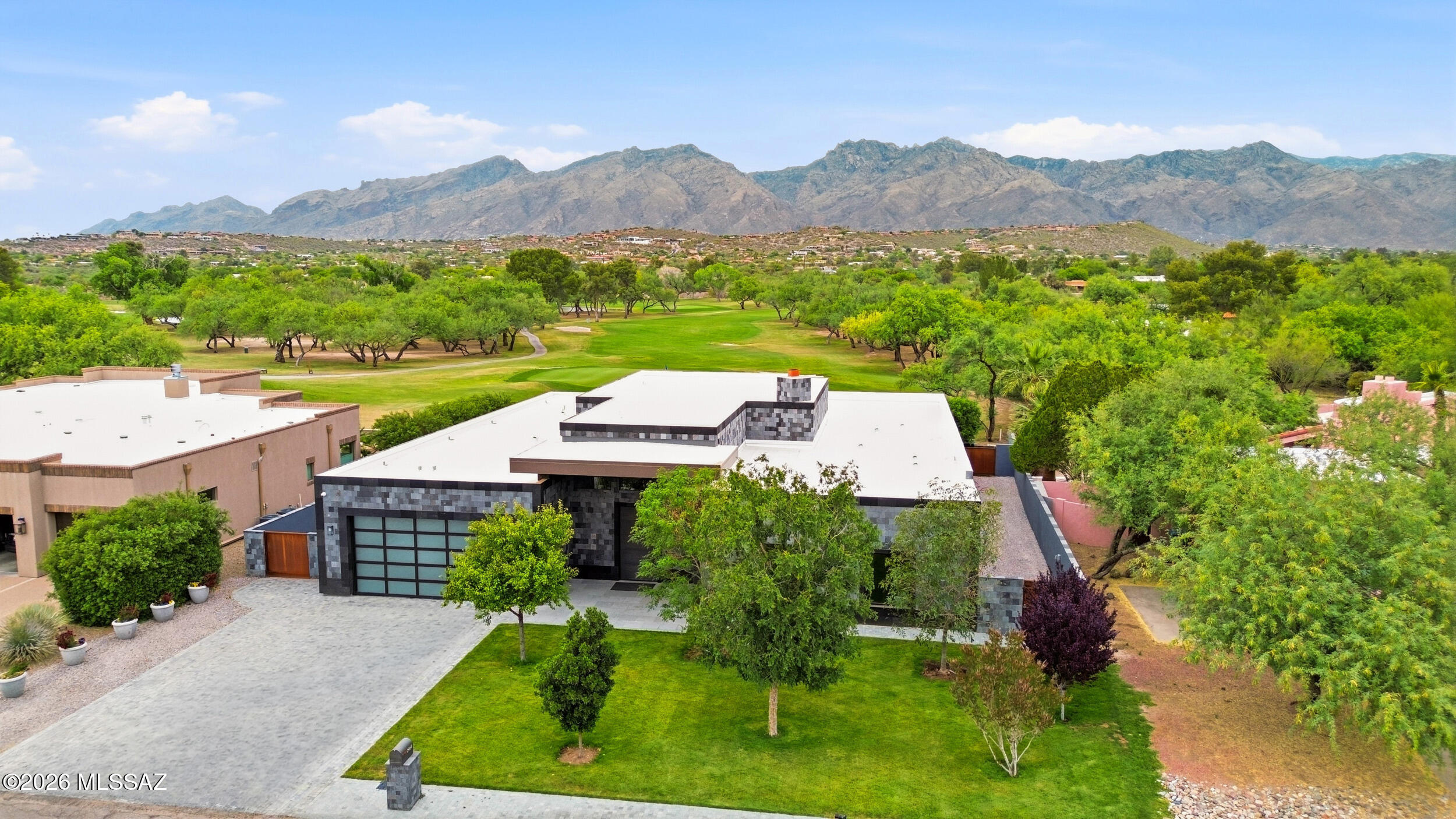 A rare, sophisticated and exclusive desert sanctuary! This contemporary 3Br/3.5Ba masterpiece sits on the 14th green in the Tucson Country Club on one of the most prestigious lots. The striking exterior showcases exquisite Indonesian lava stone, while a custom pivot front door welcomes you inside. Rich Brazilian cherry wood floors stretch under beautiful maple ceilings. Designed for art lovers, the gallery entry leads to a chef's kitchen with elite Miele appliances and an expansive great room. The massive picture windows frame jaw-dropping unobstructed views of the mountains and rolling golf course. A custom walnut closet offers luxury storage in the spa-like primary suite. Enjoy pristine lawns and a covered patio from unparalleled outdoor living and splendor.