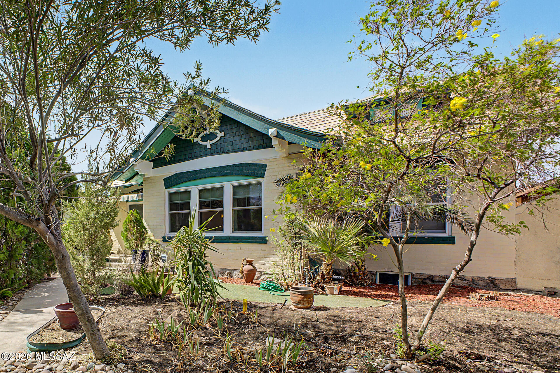 $50K PRICE REDUCTION! Fall in love with this classic home built in 1905! Walking distance to University of Arizona campus, 4th Ave, the streetcar, Health Clinic, restaurants and Market.  A true one of a kind home with beautiful original features and tastefully done upgrades.  Enjoy the wood floors, 2 beautiful crystal chandeliers, fully remodeled kitchen with newer appliances, Marmoleum flooring wall to wall and Tiffany pendant lights made by Quizel. Master bathroom is completely remodeled with Carrera marble floor to ceiling including tub. Marble flooring continues in hallway corridor and adjacent  room to master bedroom. The classic and new is combined in the other full bathroom also completely remodeled with black Italian porcelain tiles. Original house tile remains on the sink wall. Original house tile remains on the sink wall. The HVAC system, installed in 2023 by Hamstra Heating and Cooling, has been regularly maintained. The maintenance contract lasts through January 2027. The front of the main house has five new Marven windows across the living room and dining room. The remaining windows have been serviced and freshly painted. The perfect place for your book collection is in the third bedroom with custom floor to ceiling bookcases and antique chandalier. A gardeners dream. the greenhouse has all electric power, an air cooler, exhaust fan and a dual irrigation system. The floor is a resin material and will last "forever". The front sidewalk pole lights are on an auto light controlled electric eye and light up from dusk until dawn. Park your car out of the sun in the garage and use the workshop for hobbies, extra storage or home office. There is a solar powered back gate to let you in and out of the yard. In the back yard you'll have a serene landscape that makes it easy to relax and enjoy your morning brew on the paver patio, and plenty of space for added storage with sheds. Hurry up, this gem won't last!