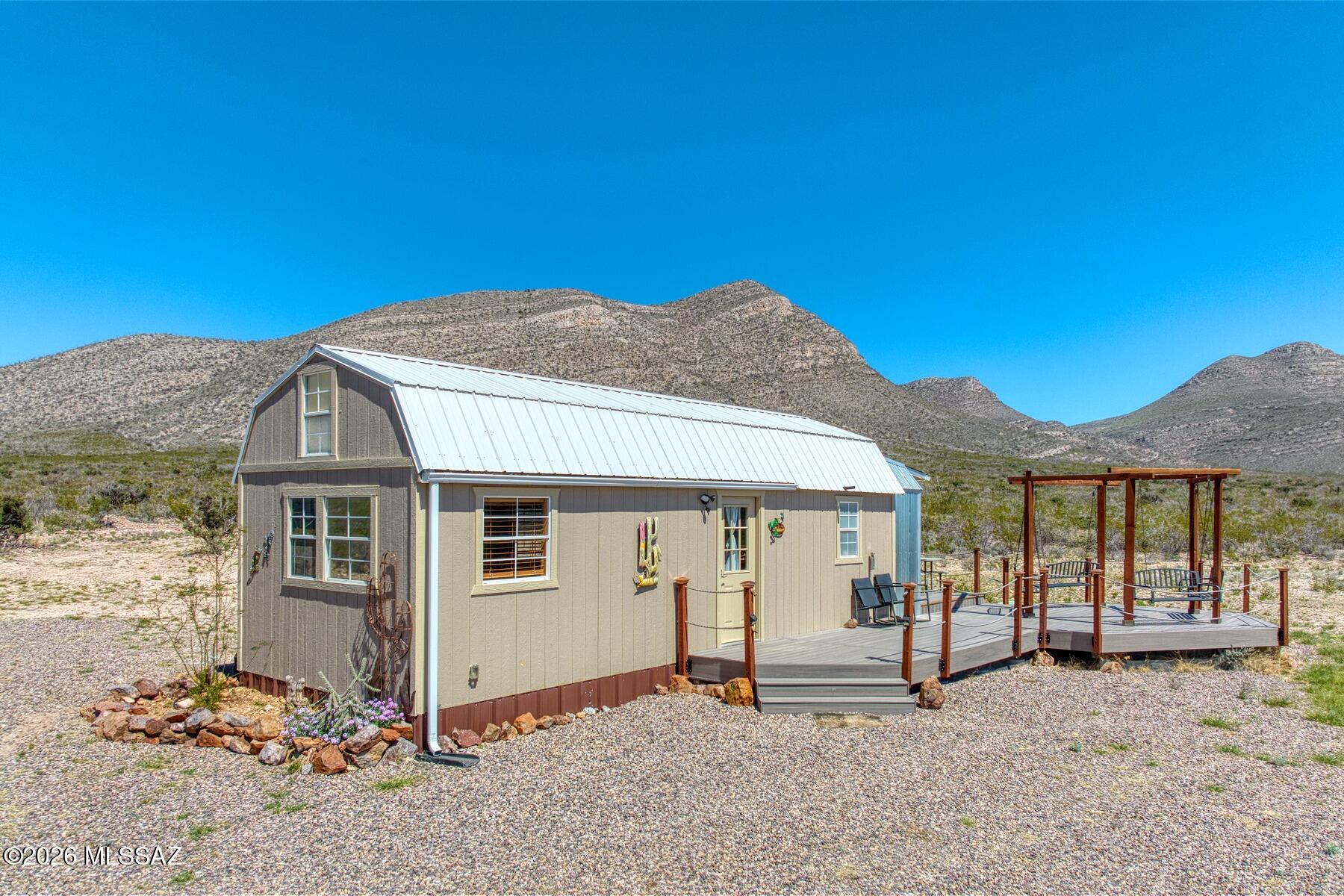 Escape to wide-open space with this charming tiny home on 9.795 acres in scenic Bisbee! Offering 384 sq ft of main living plus a 120 sq ft sleeping loft, and add'l storage loft space. This thoughtfully designed home features warm wood finishes, corrugated metal accents, and a functional full kitchen with electric cooktop, double sink, microwave, and built-in natural wood dining bar. The bathroom includes a shower, single vanity, storage and stacked washer/dryer. Operated as a successful short-term rental ''Stargazer,'' this turnkey property with panoramic views even includes furnishings. Features private well, pump house, AC, updated electric service, grill area and a big deck swing. Ideal for full-time living or wknd escape, minutes from Old Bisbee, Sierra Vista, dining and necessities!