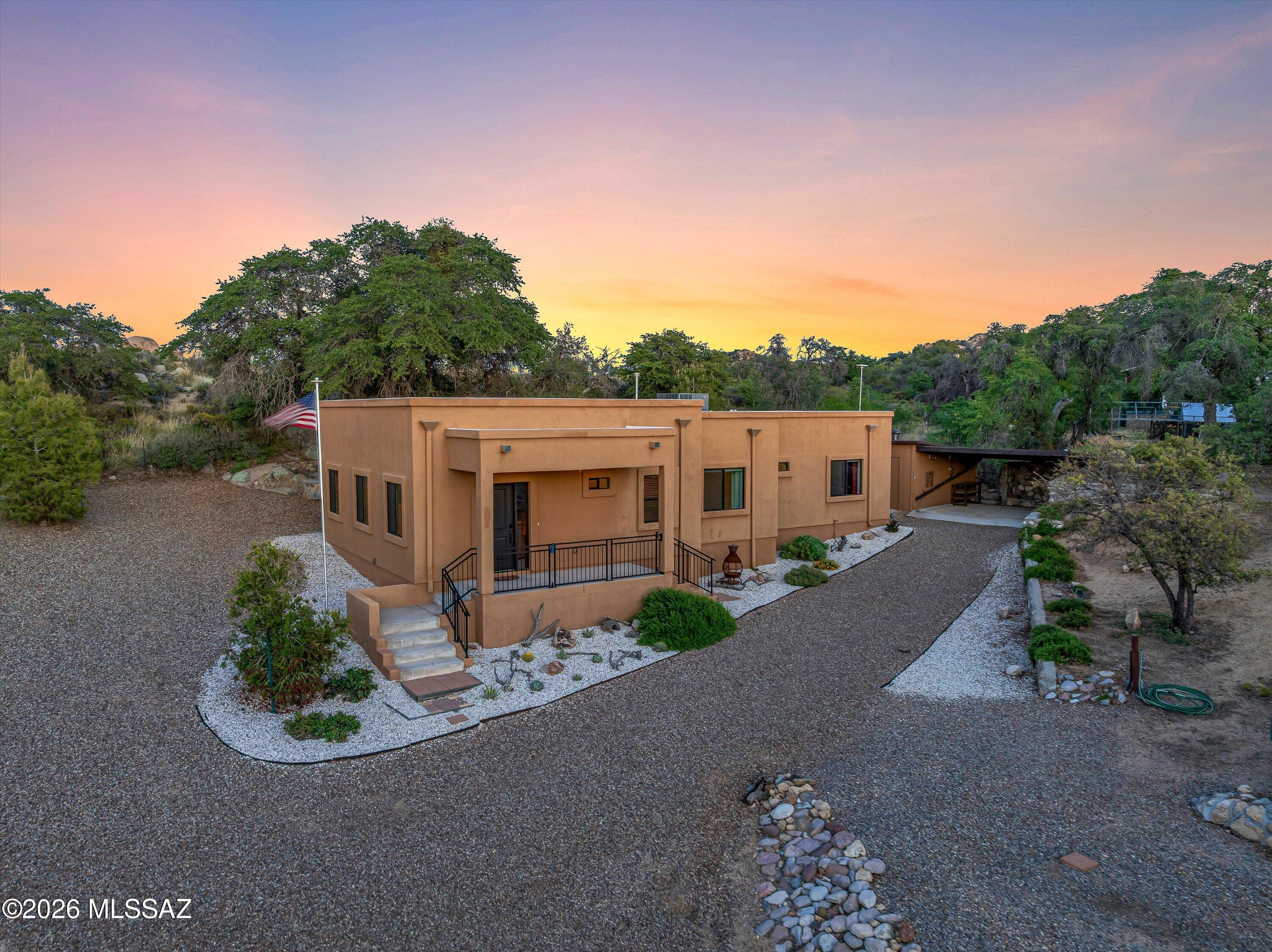 Boulders & Oaks Retreat! This cozy Santa Fe style two bedroom home sits on half an acre surrounded by beautiful boulders and mature oak trees. The living room, kitchen, and entryway feature vaulted ceilings that create an open, airy feel, while the bedrooms, bathrooms, and hallway have 9-foot ceilings for added comfort. The kitchen includes manufactured quartz countertops and the entire home has ceramic tile flooring throughout, along with central air conditioning to keep things cool during the mild summers. The backyard is a true oasis, designed with rock walls, natural boulders, oak trees, a bar area, and multiple places to sit and relax. The property also includes full RV hook-up with water, sewer, and electric, a fenced area for fruit trees and grape vines, a smaller fenced dog run, several fenced garden beds, and a chicken coop perfect for anyone who loves gardening or small homesteading projects. A large workshop with electricity, insulated walls, and an attached one-car carport adds even more functionality to the property. This home offers charm, space, and the peaceful feeling of nature all in one place.