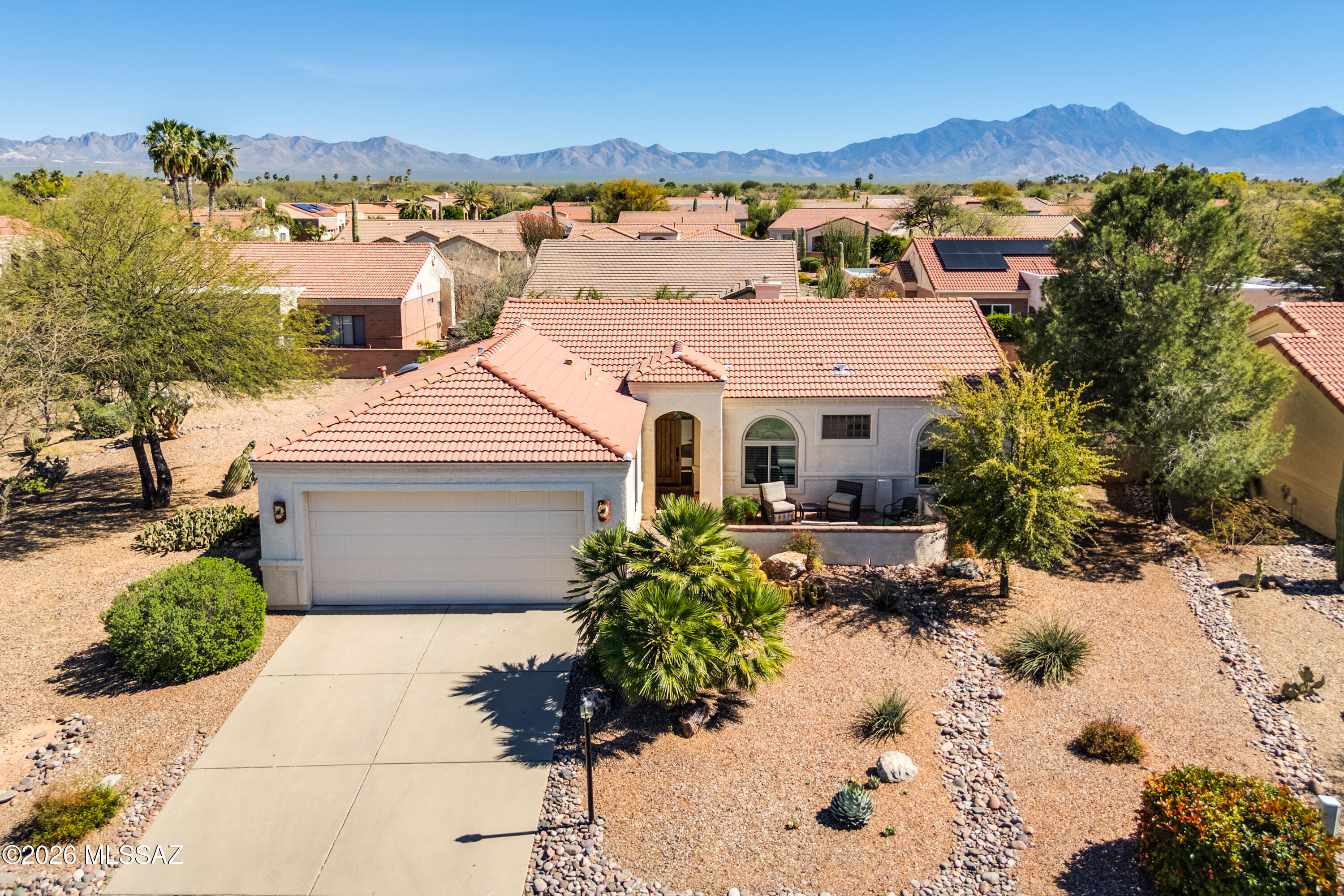Charming Cactus Wren model in the Quail Creek resort community, built in 1996 and offering 1,510 sq.ft., 2 BR, 2 BA + Den, ideally situated on a desirable corner lot adjacent to a large common area for added privacy and open space. Enter through the inviting front paver courtyard into a bright living room featuring ceramic tile flooring, built-in entertainment center, and a cozy corner beehive gas fireplace. The dining area just off the kitchen comfortably accommodates six or more, perfect for everyday living or entertaining. Kitchen is updated with quartz countertops, breakfast bar, pantry cabinet, and ample storage. The owner's suite offers a walk-in closet and dual-vanity bath with an all-tile walk-in shower. The guest bedroom is adjacent to an updated bath with tile walk-in shower. Enjoy outdoor living under the covered paver patio with built-in BBQ and extended paver patio area for outdoor dining, surrounded by lush landscaping and a mature citrus tree. Additional features include a spacious laundry room with added storage, 2-car garage, and new roof in 2022. This well-maintained home combines comfort, privacy, and the relaxed lifestyle Quail Creek is known for.