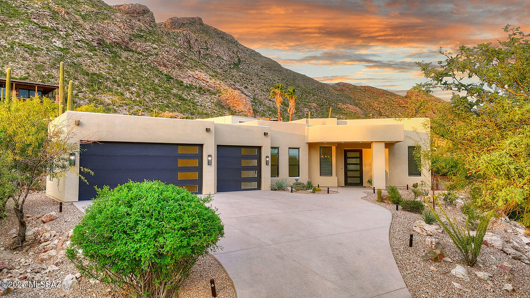 Stunning, like-new 2023 contemporary perched on La Paloma Drive, the highest street in the coveted Coronado Foothills Estates of Tucson's Catalina Foothills. Set on a glorious one-acre lot embraced by the Catalina Mountains and Coronado National Forest, this 3,605 sq. ft. residence offers 4 bedrooms, 4.5 baths, and a 3-car garage—designed to showcase sweeping city lights, mountain vistas, and dramatic sunrise and sunset views from every room.  Built by renowned master builder Paul Rondelli, the home welcomes you into a striking great room with soaring ceilings, walls of glass, porcelain tile flooring, a sleek fireplace, and an open dining area—perfect for entertaining. The chef's kitchen is both functional and modern, featuring stainless steel appliances, a spacious center island with  breakfast bar, abundant counter space, and a walk-in pantry.  The luxurious primary suite is a private retreat with a fireplace, direct access to the covered patio, and a spa-inspired bathroom boasting quartz finishes, a walk-in glass shower, a soaking tub, and a generous walk-in closet with custom built-ins. Each bedroom has an en-suite bath and a walk-in closet. Additional highlights include a large laundry room with a sink, and a light-filled garage with windows and epoxy coated floors.  Located within the Catalina Foothills School District #16, this home offers the perfect blend of contemporary style, move-in-ready convenience, and unrivaled views, all just minutes from shopping, dining, and city amenities, yet peacefully above the bustle of daily life.