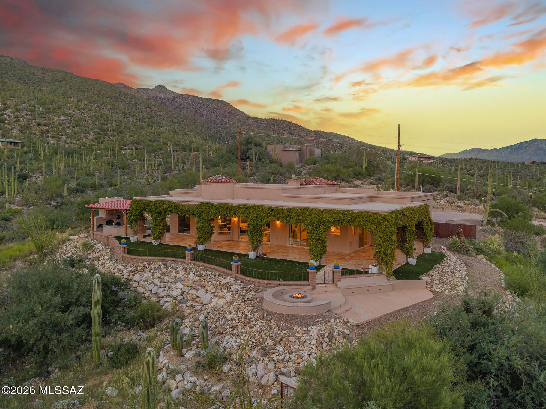 Discover sophisticated contemporary living in this stunning privately gated estate, perfectly positioned on a 1.75-acre ridge-top homesite with spectacular panoramic views of the city, surrounding mountains, and the Robert Trent Jones-designed Arizona National Golf Course. A long, private gated drive leads you to this impressive custom residence, offering approximately 3,201 sq. ft. in the main home plus an additional 513 sq. ft. attached guest house with its own private entrance.

Step through the welcoming foyer into an exceptional open-concept interior highlighted by a dramatic Great Room featuring soaring ceilings, expansive windows, designer-lit niches, beautiful tile flooring, and a striking floor-to-ceiling gas fireplace with a distinctive custom mantle. The elegant formal dining area features a coffered, illuminated ceiling, while the nearby wet bar includes a wine cooler and sophisticated finishes.

The gourmet kitchen is designed for both everyday living and entertaining, showcasing quartz countertops, a large center island, GE Café stainless steel appliances, a five-burner gas cooktop with designer hood, two ovens, refrigerator with built-in Keurig coffee maker, pot filler, dishwasher, microwave, custom tile backsplash, and eye-catching metal artwork above the island. A charming breakfast area and convenient butler's pantry complete the space.

Entertainment reaches another level with the impressive two-level theater room, featuring eight oversized leather theater seats, including a massage chair, custom TV tile inset, state-of-the-art surround sound, wet bar with refrigerator, and soundproof walls.

The main residence offers three bedrooms in a desirable split-bedroom layout and 2.5 baths. The luxurious primary suite features a custom gas fireplace with quartz surround and unique see-through openings that provide views from the Great Room through the bedroom to the sparkling city lights. Additional highlights include blackout blinds and a spa-inspired primary bath with dual vanities, a six-foot soaking tub positioned to capture the views, a spacious shower, and a custom walk-in closet with two full-length mirrors. A dedicated laundry room with sink adds convenience.

The attached 513 sq. ft. guest house offers incredible flexibility and could also serve as an excellent Airbnb or VRBO opportunity. It includes a comfortable living area, full kitchen with refrigerator, stove, dishwasher and microwave, full bath with large shower, closet, washer and dryer, plus a private porch overlooking beautiful mountain scenery. A soundproof wall separates the guest house from the main residence for added privacy.

Step outside into a resort-style backyard designed for entertaining and enjoying the surrounding scenery. A wraparound covered patio finished in travertine tile leads to a solid-block, beautifully illuminated gazebo with a complete outdoor kitchen. Features include granite countertops, a gas-starter pizza oven and fireplace, refrigerator, sink, grill, griddle, and cooktop.

A three-car garage provides ample parking and storage.

From the exceptional interior spaces to the private guest accommodations, spectacular outdoor entertaining areas, and breathtaking panoramic scenery, this extraordinary home truly offers a lifestyle of comfort, privacy, and resort-style living. And the views are absolutely unforgettable!