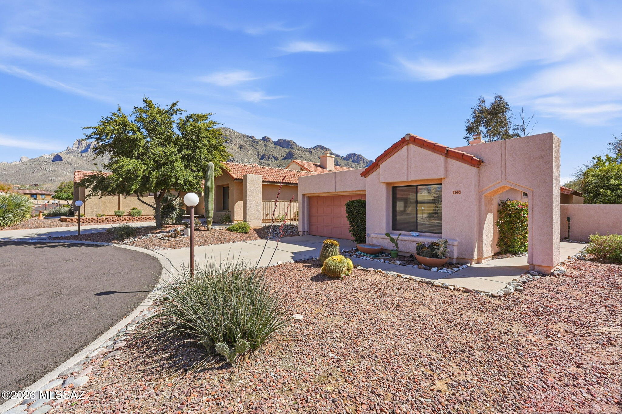 Charming 2BD/2BA (1,194 sq ft) single family home is located on a corner, cul-de-sac lot within an enclave of townhomes. Close to shopping, dining, golf, Catalina State Park and Hilton El Conquistador Resort. Soaring vaulted ceilings and large tile lend a spacious feel. Fireplace with recessed art niche highlights the open concept living space. Newer appliances include refrigerator/stove/microwave, washer/dryer & water heater. Ceramic tile throughout plus split bedroom plan. Primary ensuite hosts dual sink vanity, soaking tub/shower, custom walk-in closet plus access to rear yard with patio, block privacy wall and citrus trees. Two car garage has 240V charging outlet for electric vehicle and new garage door opener. Enjoy Pusch Ridge views from inside & out plus gated Community Pool & Spa.