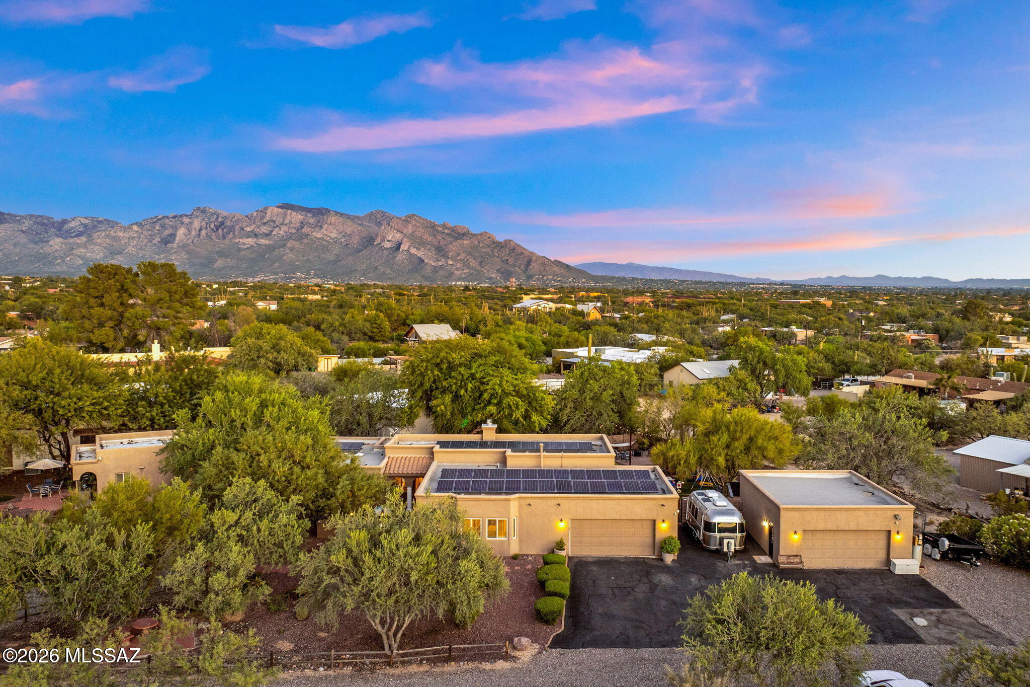 This beautiful hidden gem is a 1.31-acre estate offering complete privacy and unlimited potential. Located in the highly desirable Northwest area of Tucson, the custom Mediterranean-style home is sure to impress with a total of 5 bedrooms and 4.5 baths. It also has a true den/office, open living areas, solid custom doors, insulated interior walls throughout and so much more. As you enter the property you will see the unlimited parking, including a circular gravel driveway. You will enjoy privacy with a mature natural landscape and no HOA restrictions. Stepping inside the gated front courtyard, perfect for your morning coffee, you enter the main home. 2,738 sqft with beautiful solid hardwood flooring and carpet in the sleeping areas. Inside you will see the formal living/dining area with walls of windows letting in the natural light and views of the beautiful landscaping and patios. This room flows nicely into the open concept great room which is truly the heart of the home. With a stacked stone gas/wood burning fireplace and surround sound it is perfect for entertaining. Leading into the exquisite custom kitchen, you'll find gorgeous granite tile, a large extended island with seating, a double composite sink, reverse osmosis, mocha-stained 42-inch cabinets with crown molding and convenient pull-outs and a gas range. Additional dining area/breakfast nook includes bench seating and built-in storage cabinets, and also access to the rear patio and backyard. The owner's suite is your private sanctuary featuring a French door to a private patio, double vanity, soaking tub, and a stand-alone double shower. Relax with the attention to detail from the plantation shutters & decorative molding to the oil-rubbed bronze fixtures & modern lighting.The home has a split floor plan for privacy, featuring three additional guest bedrooms (all with walk-in closets) and a full guest bath with dual vanities and a shower/tub combo located in the hall for your convenience. Stepping outside you will find a luscious, fully landscaped and fenced backyard that includes smart drip irrigation, a 3-tier water fountain, garden beds & lush green grass, a greenhouse, a play area, and an extended patio with a gas stub. Picture yourself hosting parties in this space or simply relaxing and enjoying Tucson's colorful sunrises and sunsets. At the front of the property is a separate one-bedroom Casita with a living area, full kitchen, bathroom and private patio. The 500sq casita is perfect for a home office, studio, or accommodating overnight guests. With its own Split heating/cooling system it's also ideal for Generational living. The Casita is currently used for income and can generate as much as $30k a year. It is currently being used as an Airbnb. Now let's talk about the garages. The two-car attached garage is extended and extra wide, offering plenty of room for two vehicles (including a long bed truck) and storage, it also houses the home's water softener. Adjacent to this garage is an additional garage/workshop. The detached garage is fully insulated, holds four cars, and comes equipped with 220-amp and 110-amp electric hookups, water, cable, a mini-split, and an evap cooler making it the perfect man cave or work space. The Amazing Property includes an 1800-gallon water cistern tank, a solar electric system ($171/m + $24 to TEP), a water softener (reverse osmosis), RV hookups (electric, water and cable) and separate Christmas light circuits for the home, casita and workshop. Some furniture within the house and garages is available with a separate bill of sale. What are you waiting for? With all these features, high ceilings, skylights, ceiling fans, no HOA, privacy and income potential, this home won't last long!