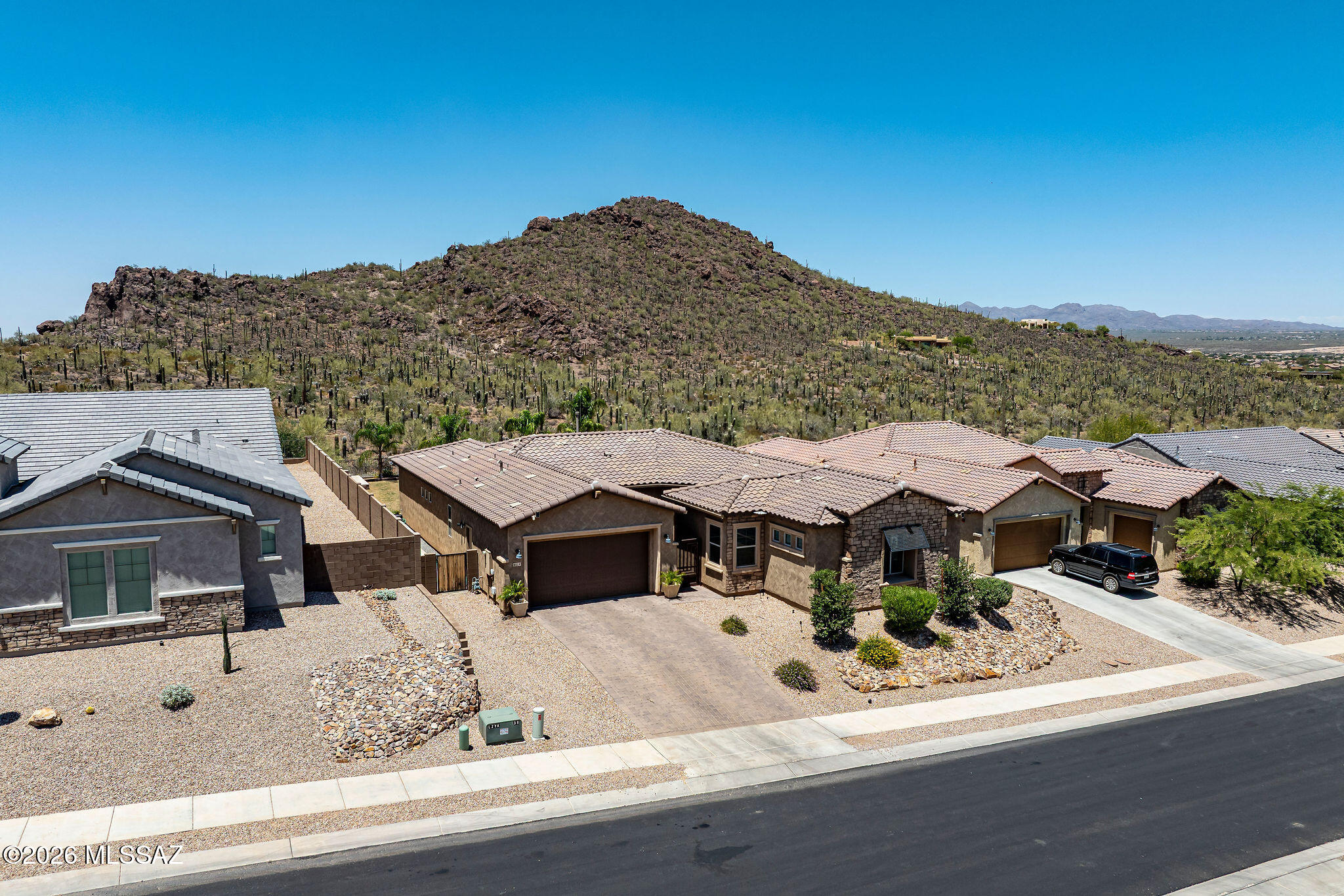 Views, Views, Views! Situated on one of the premier lots in the subdivision, this exceptional home is positioned on a premium ¼ acre cul-de-sac lot with no rear neighbors and breathtaking, unobstructed mountain views. Located within the gated enclave of Lazy K Bar Ranch, bordering the stunning landscapes of Saguaro National Park, this property offers remarkable privacy and tranquility while remaining conveniently close to shopping, dining, schools, and I-10. This newer home is extensively upgraded and showcases custom finishes throughout. A gated courtyard entry with a welcoming sitting area and attractive stone accents creates outstanding curb appeal. Inside, the gourmet kitchen is designed to impress, featuring an abundance of custom cabinetry, an oversized quartz island with seating for five, undermount sink, pendant lighting, and stainless steel appliances including a gas cooktop, decorative hood, built-in convection oven and microwave, dishwasher, and French-door refrigerator.
The luxurious primary suite serves as a private retreat, featuring a huge bedroom with ample space for a sitting area and views of the surrounding mountains. The spa-inspired primary bathroom offers custom vanities with quartz countertops, dual sinks, upgraded designer faucets, and a large walk-in shower with elegant tile surrounds extending to the ceiling, creating a sophisticated and modern atmosphere.
Designed for seamless indoor-outdoor living, the backyard is one of the largest in the community and captures spectacular mountain views and unforgettable Arizona sunsets. Enjoy lush grass, open-view fencing, mature trees and landscaping, stone patios, and a raised deck with a firepit--perfect for entertaining or relaxing under the desert sky. The large covered patio, complete with an impressive eight-blade ceiling fan, provides year-round comfort and enjoyment. Additional features include a spacious walk-in laundry room and flexible living spaces that accommodate a variety of lifestyles. Offering unparalleled views, refined finishes, exceptional outdoor amenities, and an unbeatable location, this remarkable home embodies luxury desert living where beauty, comfort, and convenience come together.