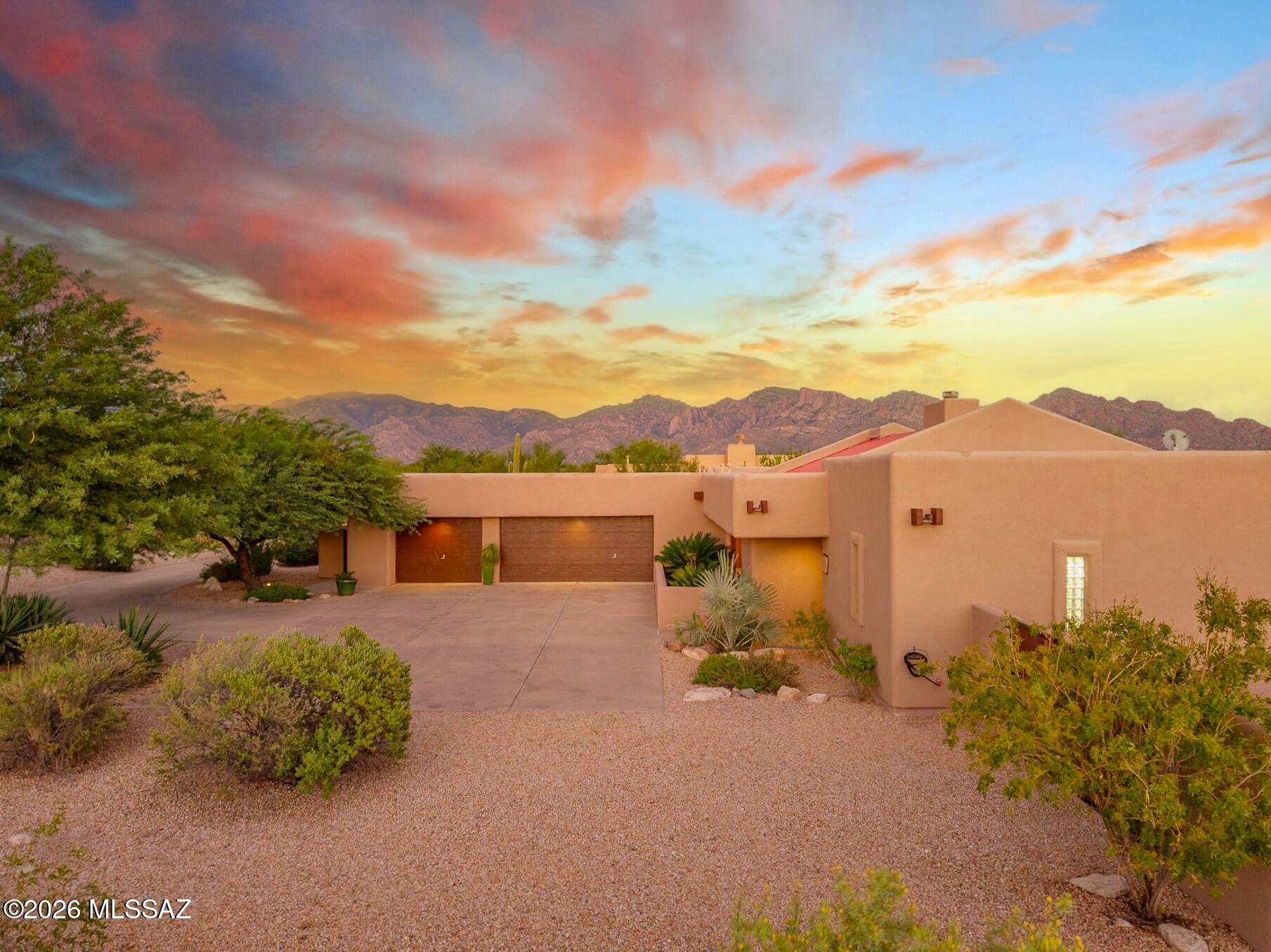 PRIVATE DESERT CONTEMPORARY | TYSON/MURPHY DESIGN | VIEWS + RESORT BACKYARD: Located on a private, quiet lot of nearly half an acre, this distinctive Tyson/Murphy-built home pairs timeless desert contemporary architecture with a resort-style backyard. Dimensional walls, exposed wood beams, vaulted ceilings, skylights, and glass walls create architectural interest and abundant natural light. Outside, a 2021 Pebble-Tec pool with a lagoon and water features anchors an exceptional south-facing backyard designed for year-round outdoor living, with mountain, sunrise, and sunset views, multiple patios, a built-in gas grill, wood-burning fireplace, and a putting green. A long, level driveway provides privacy, a large turning radius to the oversized 3-car garage, and abundant additional parking. Located along one of Oro Valley's most beautiful streets, the home is surrounded by established desert landscaping that creates an inviting approach and continues throughout the area. Paved roads, excellent walkability and cycling opportunities, and quick access to The Loop complement a location near Naranja Park, both the Oro Valley Community and Aquatics Center, numerous golf courses, schools, dining, and shopping.

Highly regarded for quality construction and architectural interest, Tyson/Murphy's thoughtful design is evident throughout. Floor-to-ceiling and transom windows, skylights, vaulted ceilings, and atrium-style doors draw the outdoors in, while a dramatic two-way masonry gas fireplace separates the living room and great room. The split-bedroom floor plan provides welcome separation and privacy, and every bedroom features a walk-in closet, with all but one having a custom closet system. Wood-plank flooring extends throughout with no carpeting, and built-in speakers provide surround and whole-home sound.

The kitchen combines warmth and functionality with solid natural cherry cabinetry, granite-slab counters, and newer stainless steel appliances, including a 5-burner gas range, wall ovens, and a convection oven. A built-in buffet, display cabinet, and bookcase add both character and storage, with casual dining available at the breakfast nook and counter seating.

Both bathrooms have been refreshed with quartz countertops and newer fixtures. The spacious primary bath offers 5-pc amenities, including a walk-in shower with built-in bench and additional storage. A dedicated laundry room includes a utility sink and both gas and electric connections.

The professionally landscaped mature desert plantings are supported by a newer irrigation system, while numerous paved patios create inviting spaces for dining, entertaining, and relaxing. The fully enclosed yard includes a double-hinged gate for additional parking or storage, plus a separate east-side fenced area ideal for a garden with morning sun and afternoon shade.

An oversized 3-car garage is completely open, with no interior columns or barriers, providing exceptional flexibility for vehicles, a workshop, and storage. The long, level driveway offers an ample turning radius and generous additional parking, which is an especially valuable feature in this intimate flag-lot setting.

HVAC and water heater were replaced in 2019, and the roof has been routinely maintained.

Come see this rare combination of privacy, architectural character, mountain views, quality construction, and resort-style outdoor living in one of Oro Valley's most desirable settings.