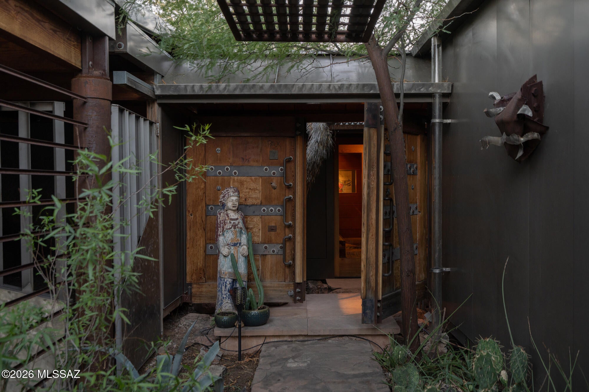 Once the personal residence of award winning Architect and builder Ron Fridlind, this private central Tucson compound was transformed and expanded over several decades. The work reflects a deeply personal architectural language shaped by Japanese design, desert living and an enduring respect for craft. 

Set well back from the street on a secluded .86 acre parcel, the 2,516 square foot main residence is surrounded by mature desert landscape, courtyards and raised garden beds. Large panes of glass draw the gardens into the home, allowing shifting light and views of the landscape to shape the interior throughout the day. Natural materials and carefully considered details unfold throughout the two bedroom, two bath home. Straight grain Douglas fir wraps walls, ceilings and floors, while stone, rustic saguaro rib ceilings and sculptural steel elements give each room its own character. Three custom metal fireplaces are woven throughout the house as both functional objects and works of art.

The procession through the house begins at a recessed entry tucked beneath a steel trellis and within native plantings. From the foyer, expansive views extend into the garden, with the primary suite to the right, the guest suite to the left and the living, kitchen and dining spaces ahead. Quiet and secluded, the guest suite looks west into the southern courtyard. Conceived as a private retreat, the spacious primary bedroom also has views into the surrounding gardens. The bathing space includes a custom stainless steel shower, wood sauna and wood fired soaking tub. Two large sliding glass panels allow this intimate space to open completely to the outdoors.

A separate 768 square foot studio provides a climate controlled space for creative or professional work, complete with a mini-split system and half bath. An additional 280 square foot detached building offers further studio, workshop or storage possibilities. Four covered parking spaces and an electronic entry gate complete the property. The parcel has been surveyed and can be divided, creating the potential to develop or sell the rear portion of the property with separate access from Monte Vista.

This property is a wonderful example of an expressive architectural composition. Tactile and deeply connected to its desert setting. It offers a rare degree of privacy, space and creative possibility in the heart of Tucson.
