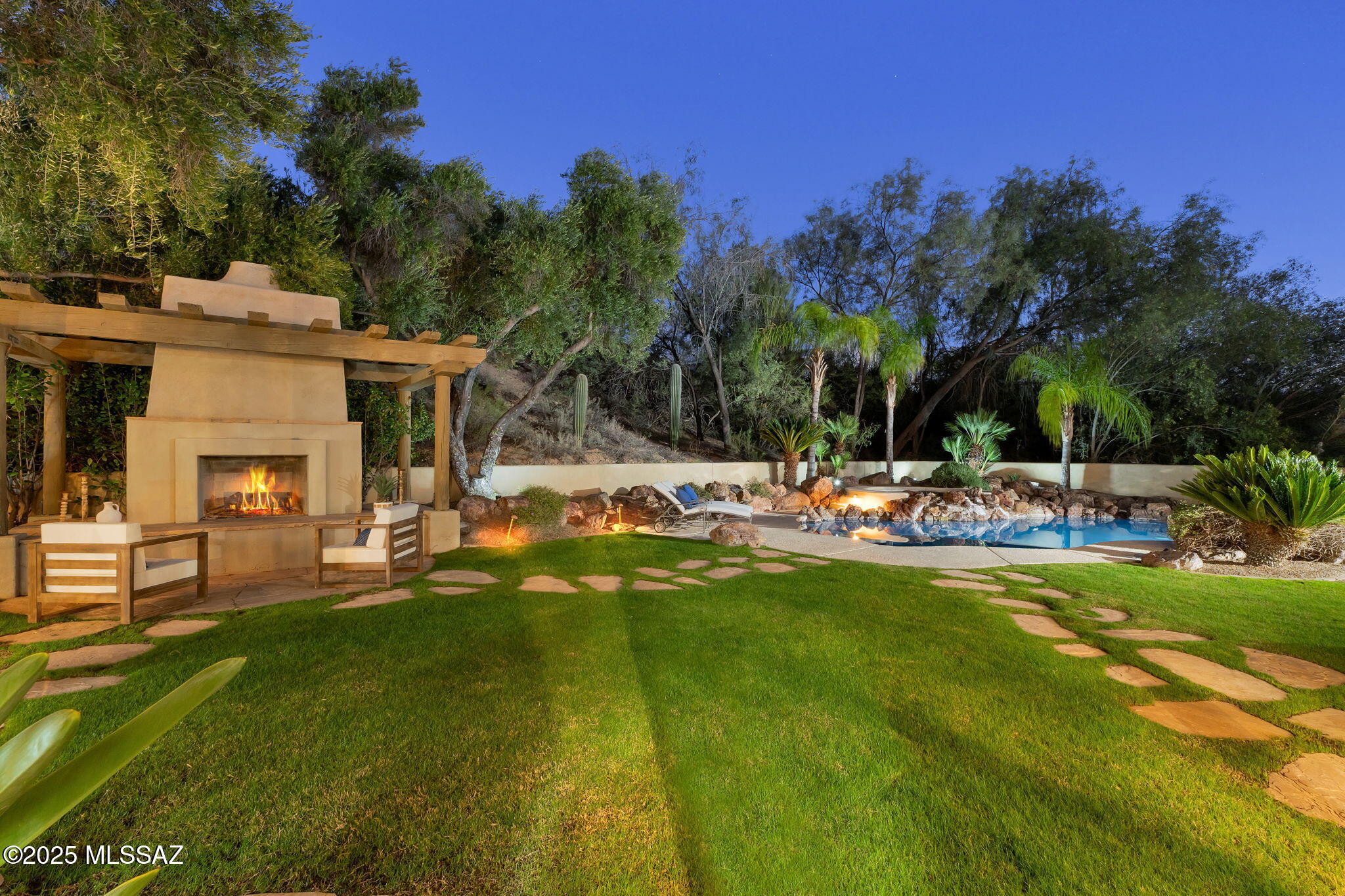 Discover this stunning custom residence in the highly desirable gated community of Cañada Hills Estates. Tucked away on a quiet, low-traffic cul-de-sac and situated on over a half-acre, this impeccably maintained home offers 4 bedrooms, 4 baths, a den/office, 3-car garage, and a full private guest house—a rare and exceptional find. Step through the custom-designed courtyard into a home showcasing warm elegance, designer finishes, and gorgeous custom solid-wood doors throughout. The spacious chef's kitchen features stainless steel appliances, granite countertops, 42'' cabinetry, a large island with cooktop & vegetable sink, an oversized pantry, and a bright breakfast nook. Off the kitchen is a generous great room with fireplace, along with a separate formal dining room and a welcoming formal living room. The primary suite is a serene retreat, complete with a cozy two-way fireplace, a huge walk-in closet, and peaceful views of the backyard oasis. The private attached guest house is ideal for multigenerational living, visiting guests, or a private office, and includes its own entrance, full bath, kitchenette, large closet, and access to a private courtyard. The resort-style backyard is truly magazine-worthyan ultimate Arizona retreat featuring a self-cleaning pool and spa, expansive wraparound patio, lush real grass and mature vegetation, a custom BBQ, designer outdoor fireplace, and multiple seating and entertainment zones. Additional highlights include central vacuum, water softener, and exceptional craftsmanship throughout. This home has been impeccably cared for and is completely move-in ready. A rare findelegant, private, functional, and beautifully designed for elevated Arizona living.